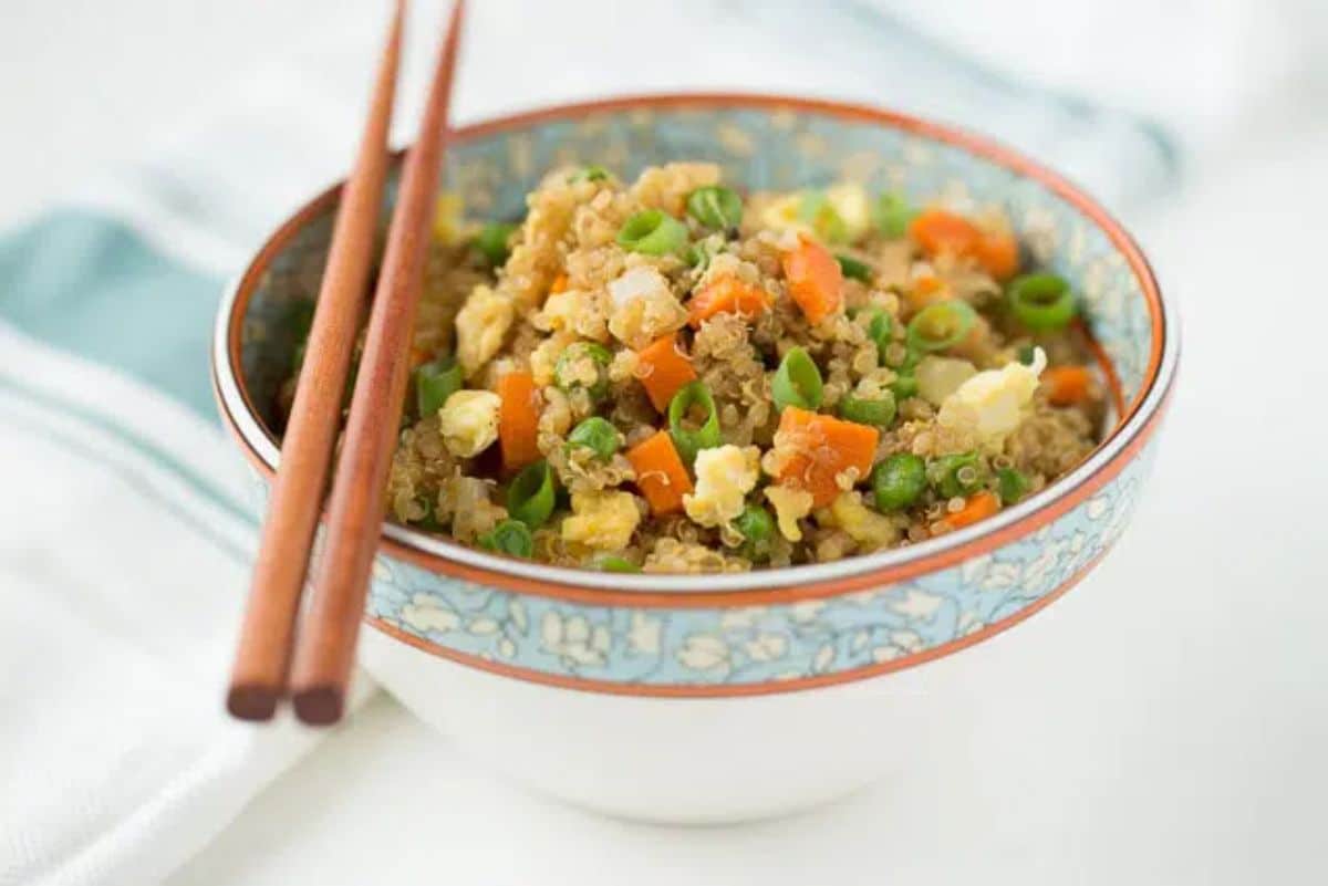 Healthy fried quinoa in a bowl with wooden chopsticks.