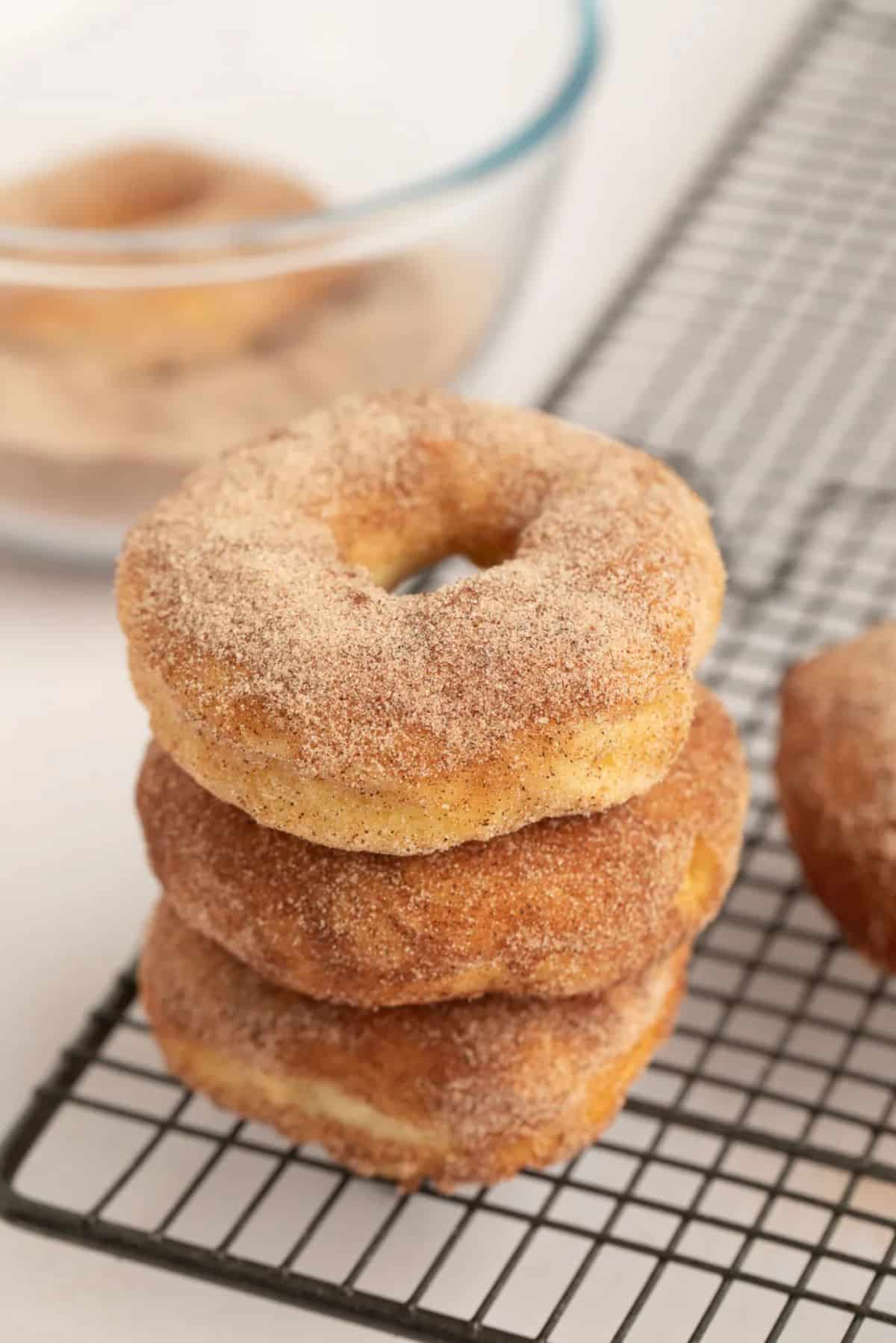 A pile of unglazed donuts on a resting grid.