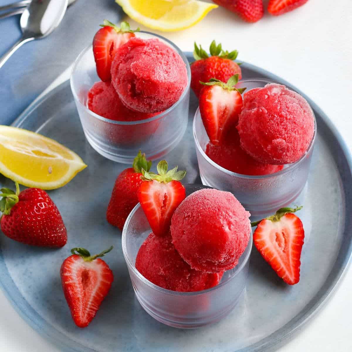 Fresh strawberry sorbet in glass cups on a gray tray.