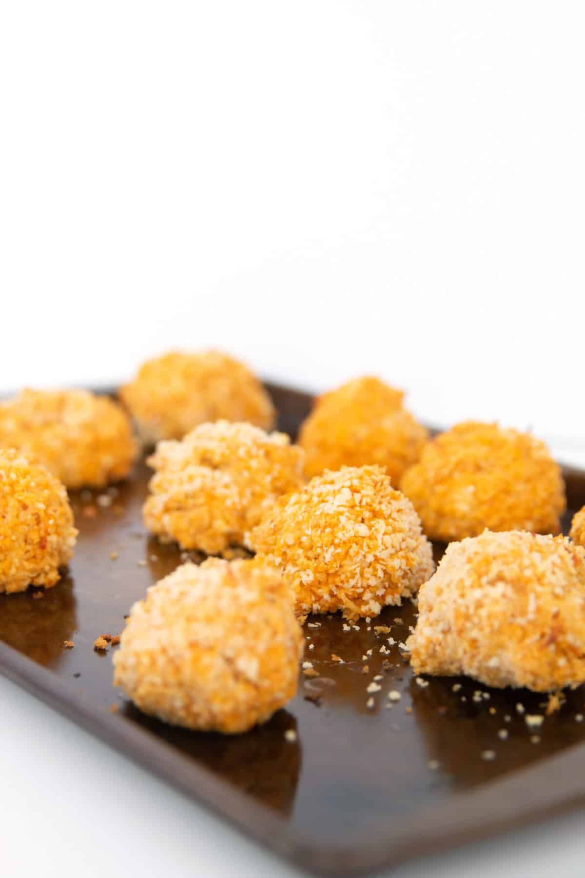 Crispy buffalo chicken quinoa bites on a wooden tray.