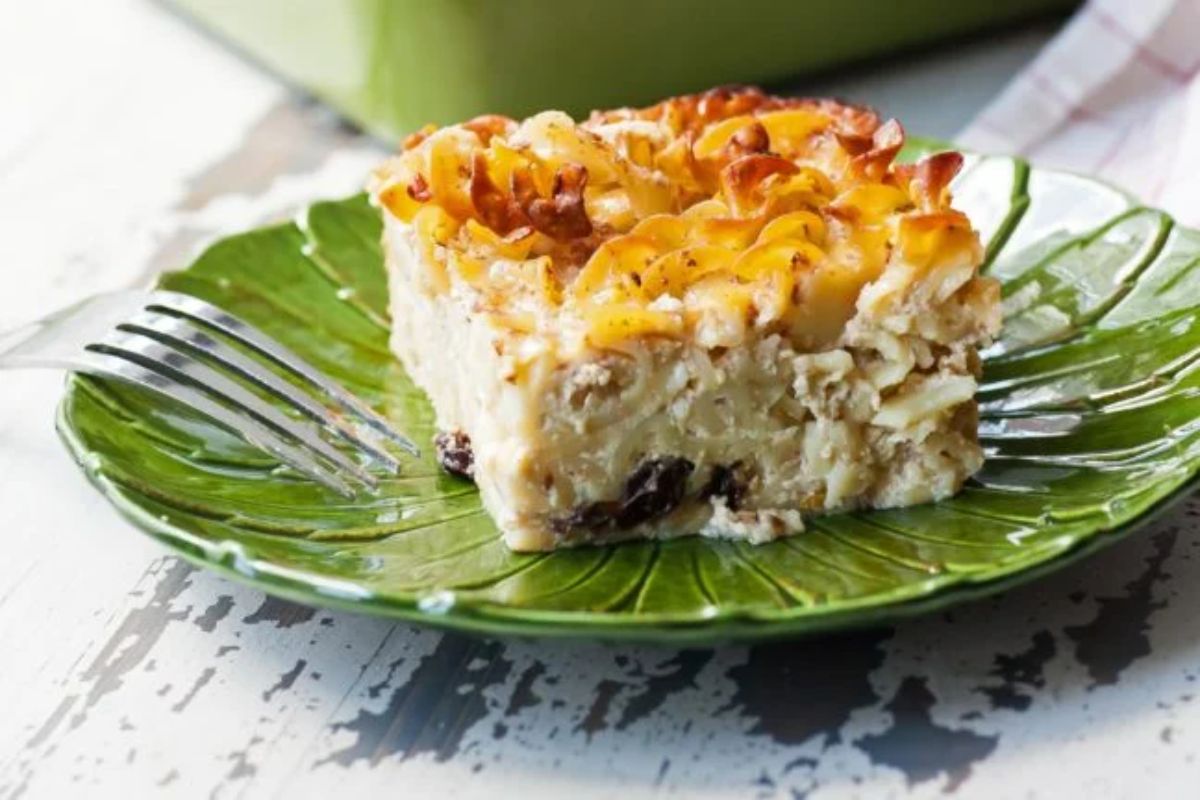 A piece of sour cream noodle kugel on a green plate with a fork.