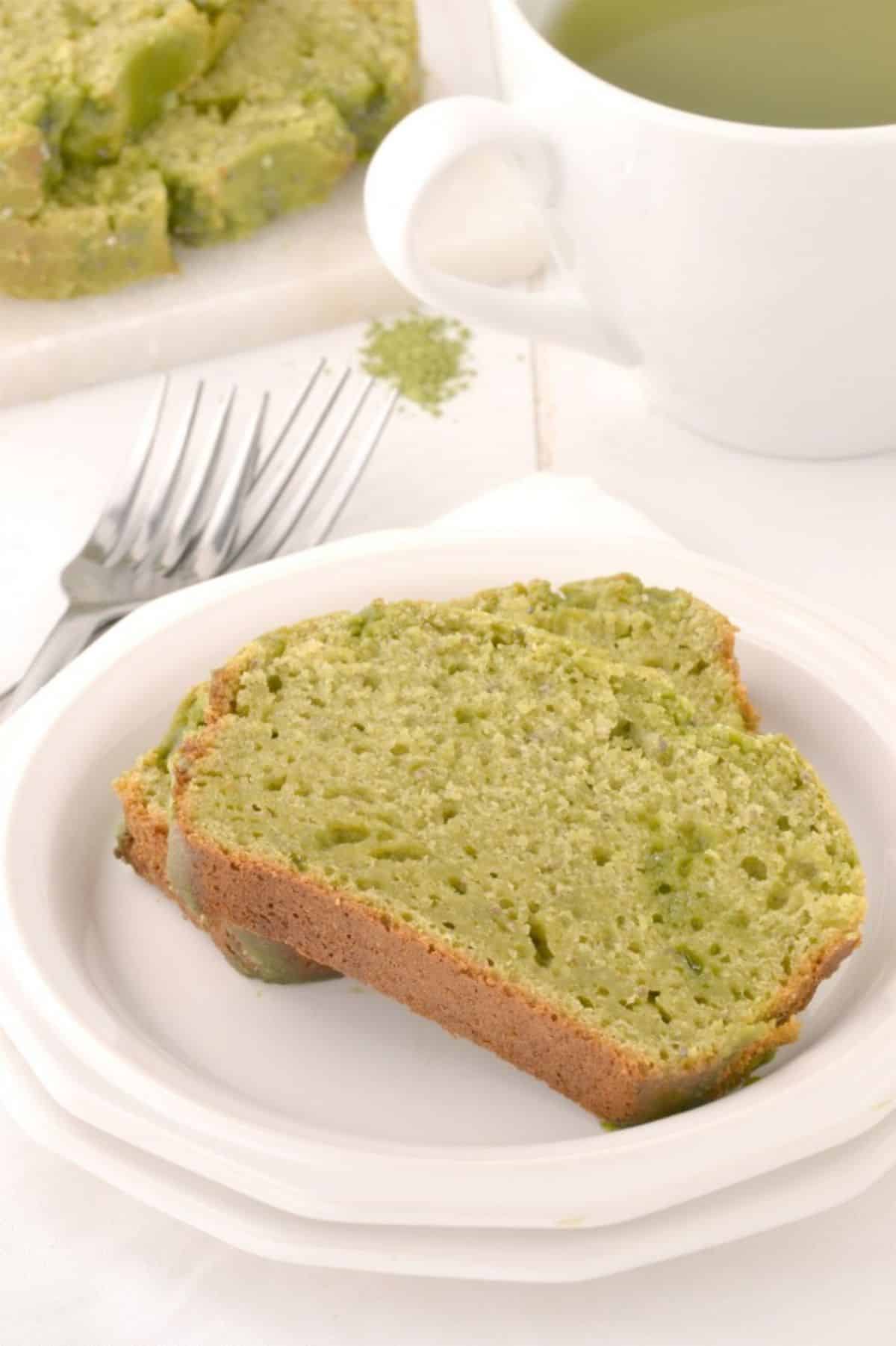 Two pieces of green tea yogurt cake on a white plate.