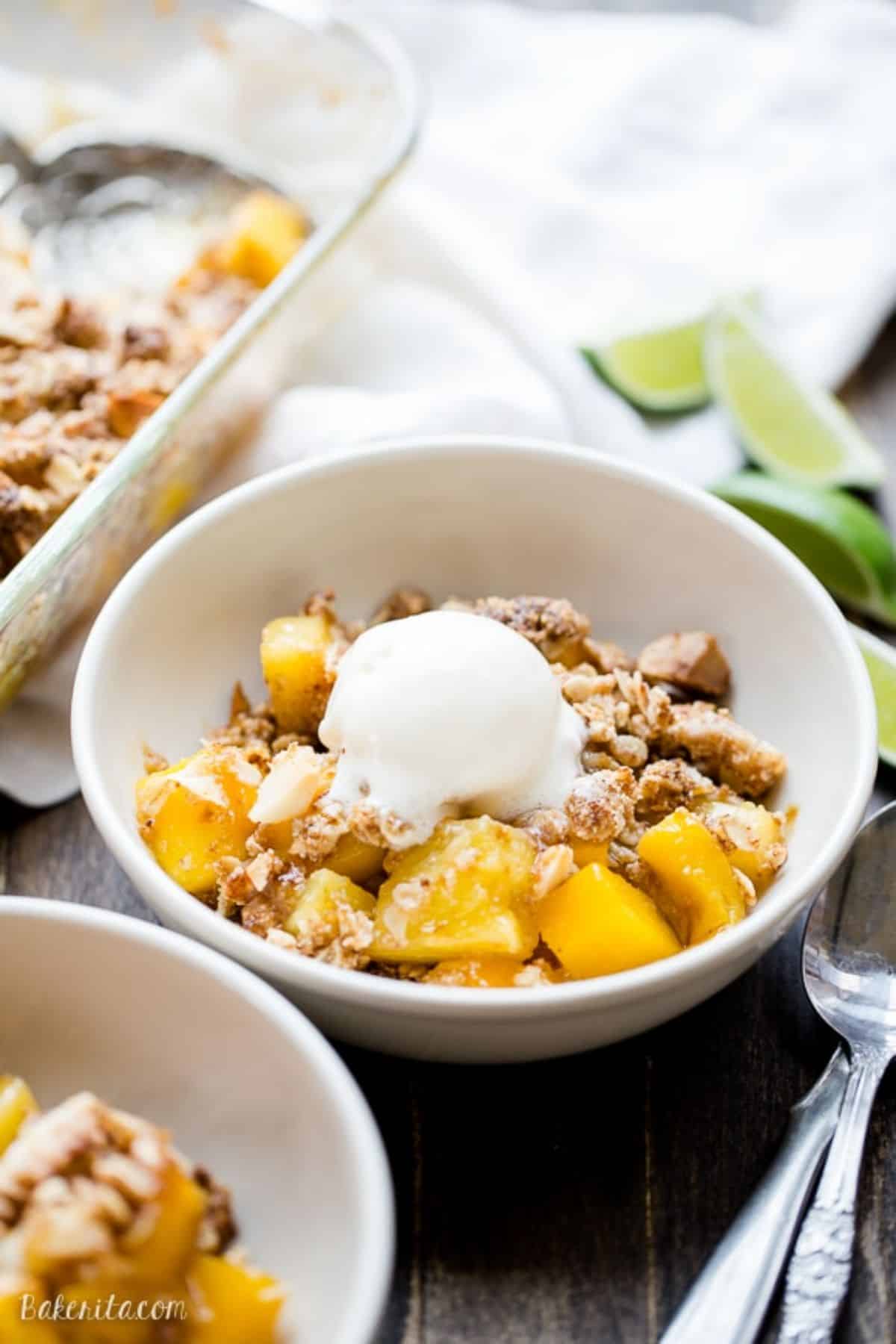 Mouth-watering mango and pineapple crumble in a white bowl.