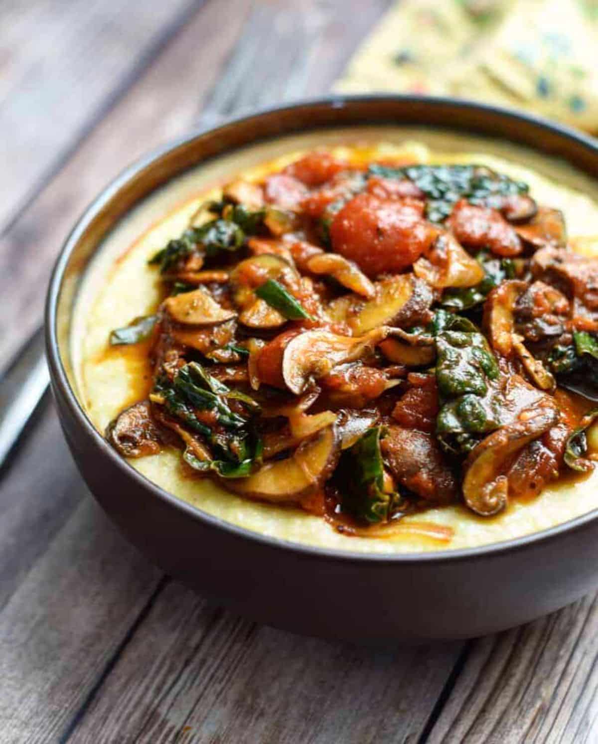 Mouth-watering mushroom ragu with creamy polenta in a brown bowl.