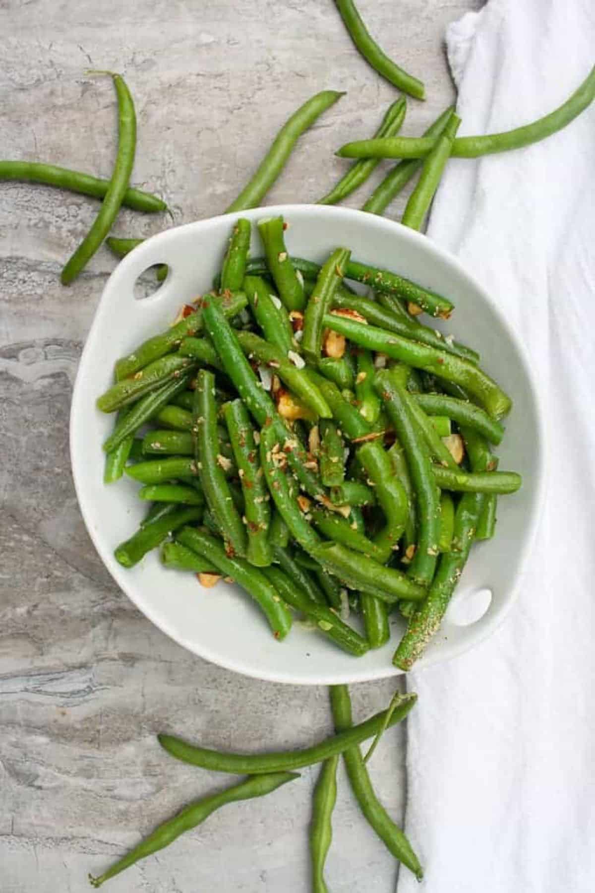 Healthy green bean salad with almonds in a white bowl.