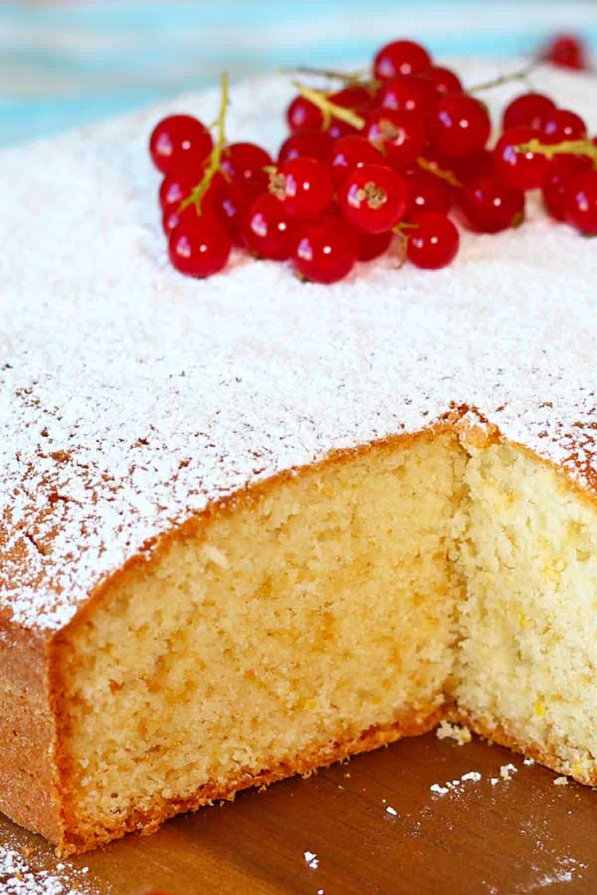 Scrumptious lemon yogurt cake in a wooden tray garnished with currants.