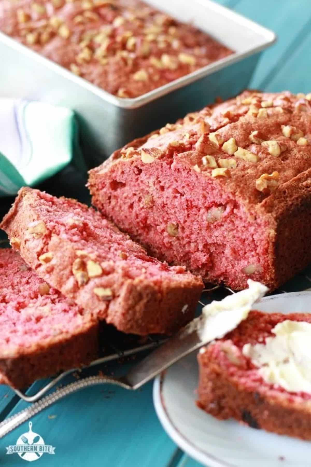 Delicious strawberry bread partially sliced on a table.