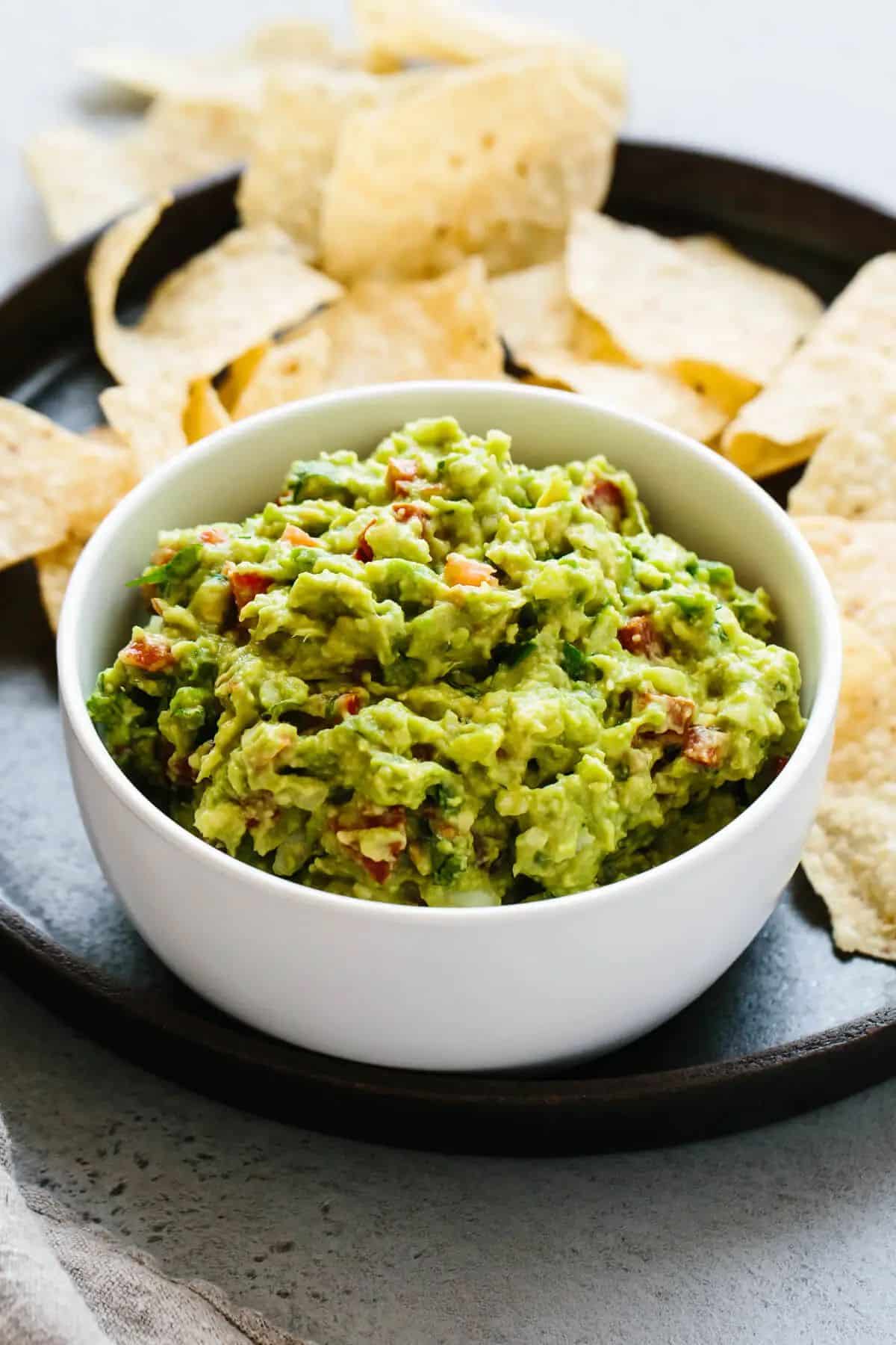 Healthy and fresh guacamole in a white bowl.