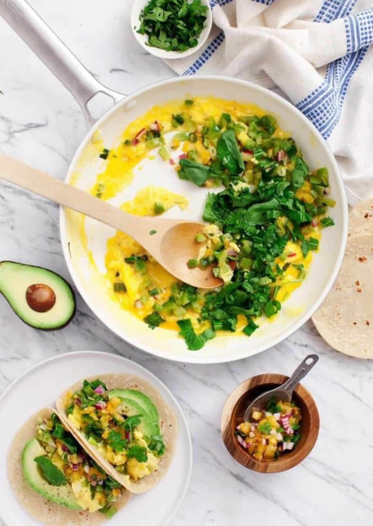 Delicious veggie breakfast tacos with ingredients on a countertop.