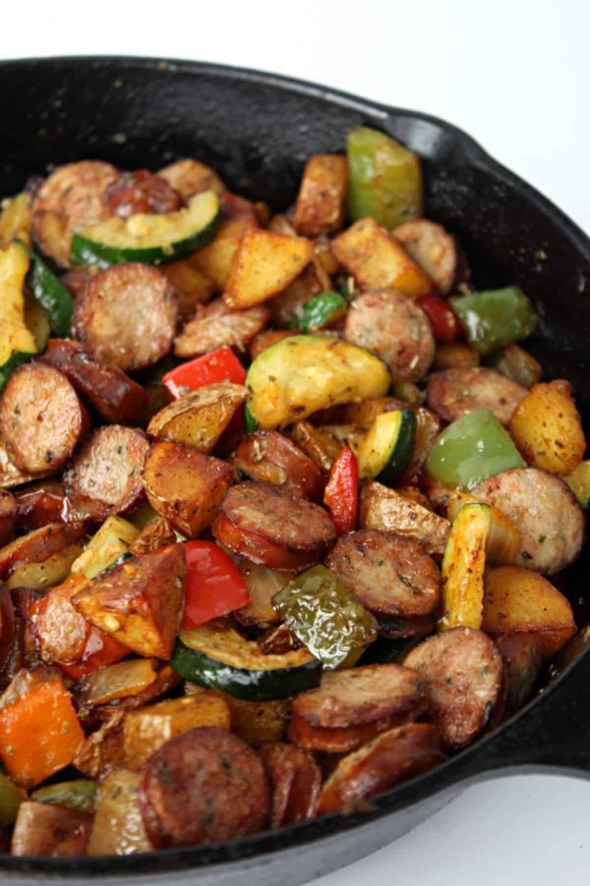 Delicious chicken sausage and vegetable in a black skillet.