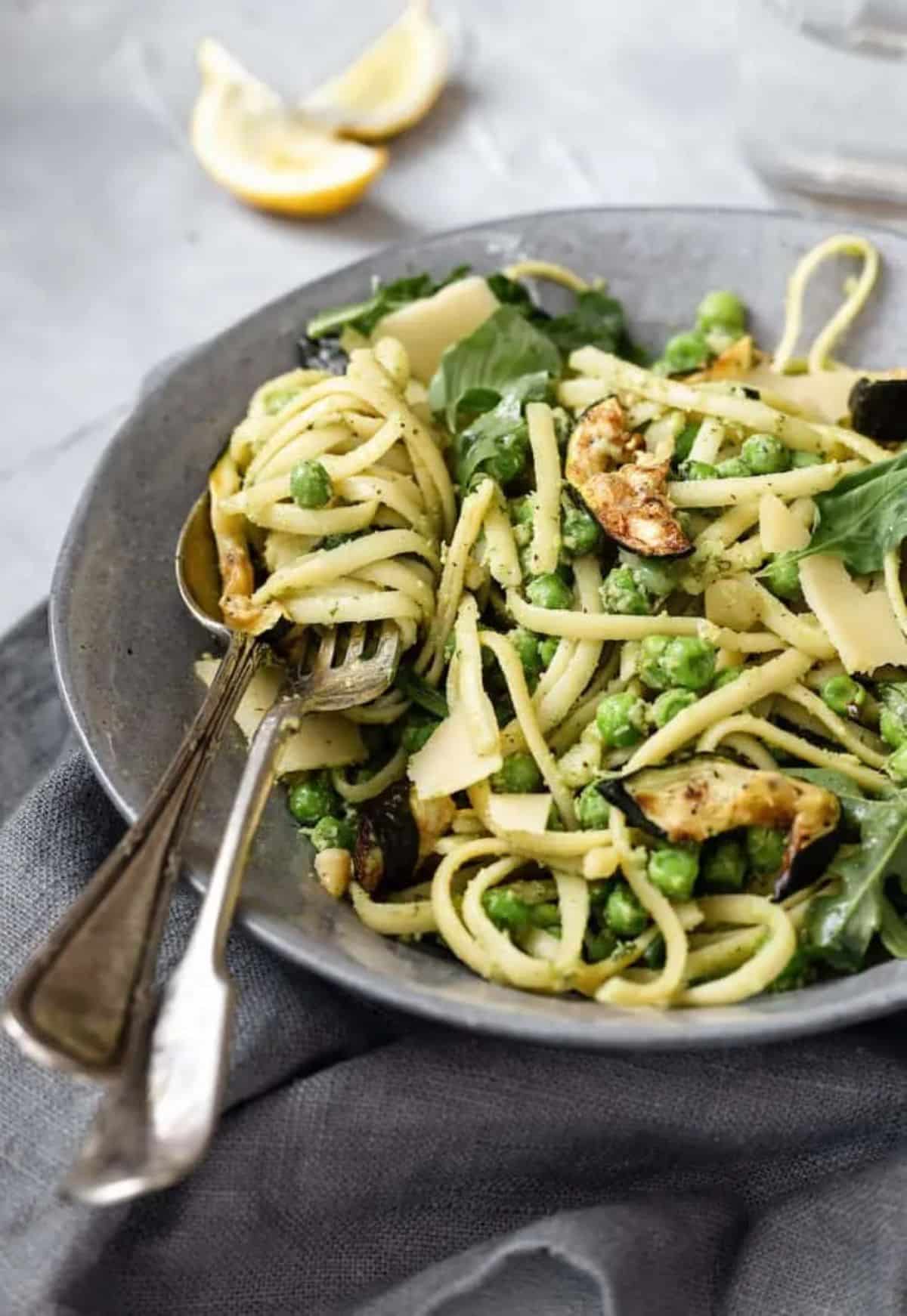 Healthy brazil nut pesto pasta in a gray bowl with cutlery.
