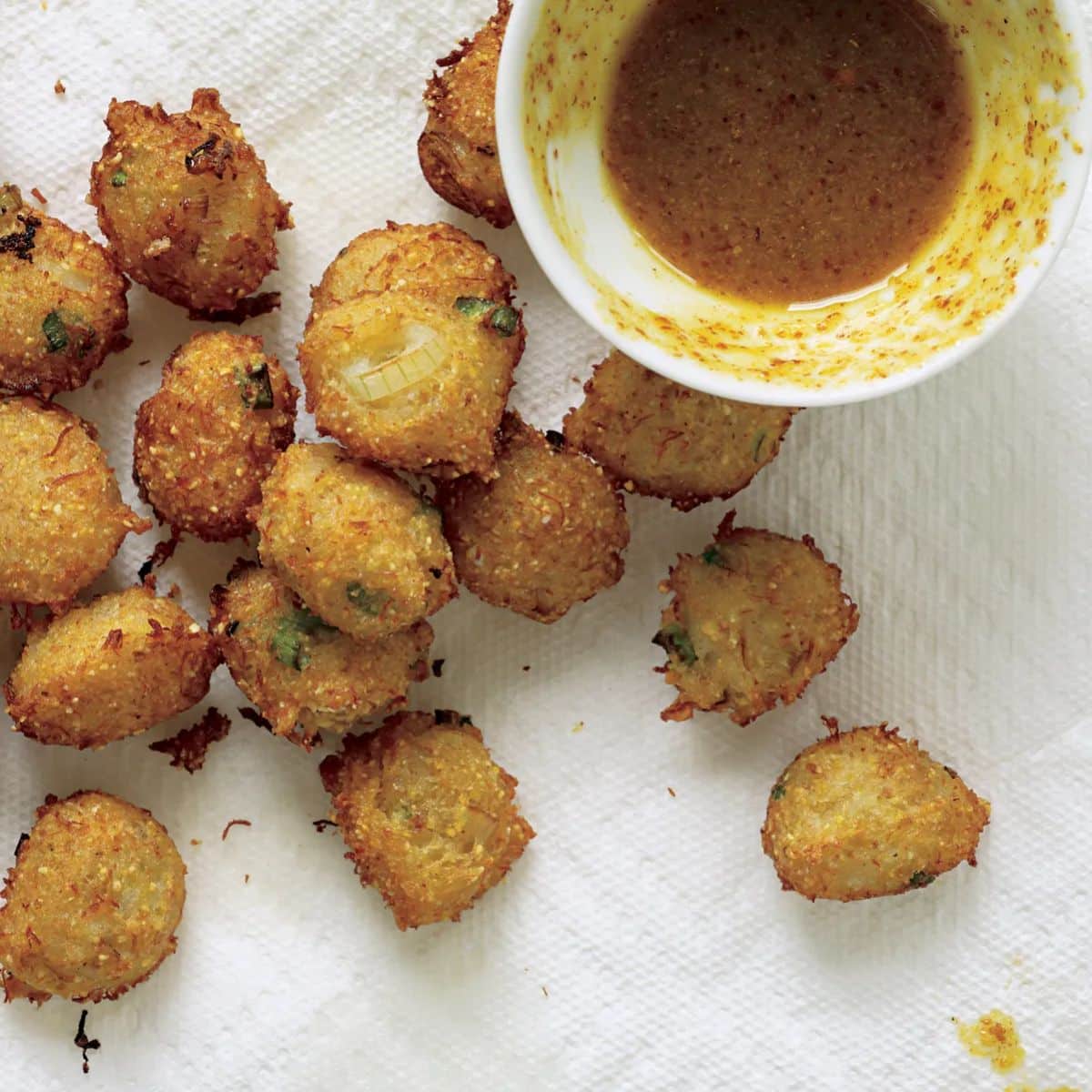 Crispy crab hush puppies with a bowl of dip on a table.