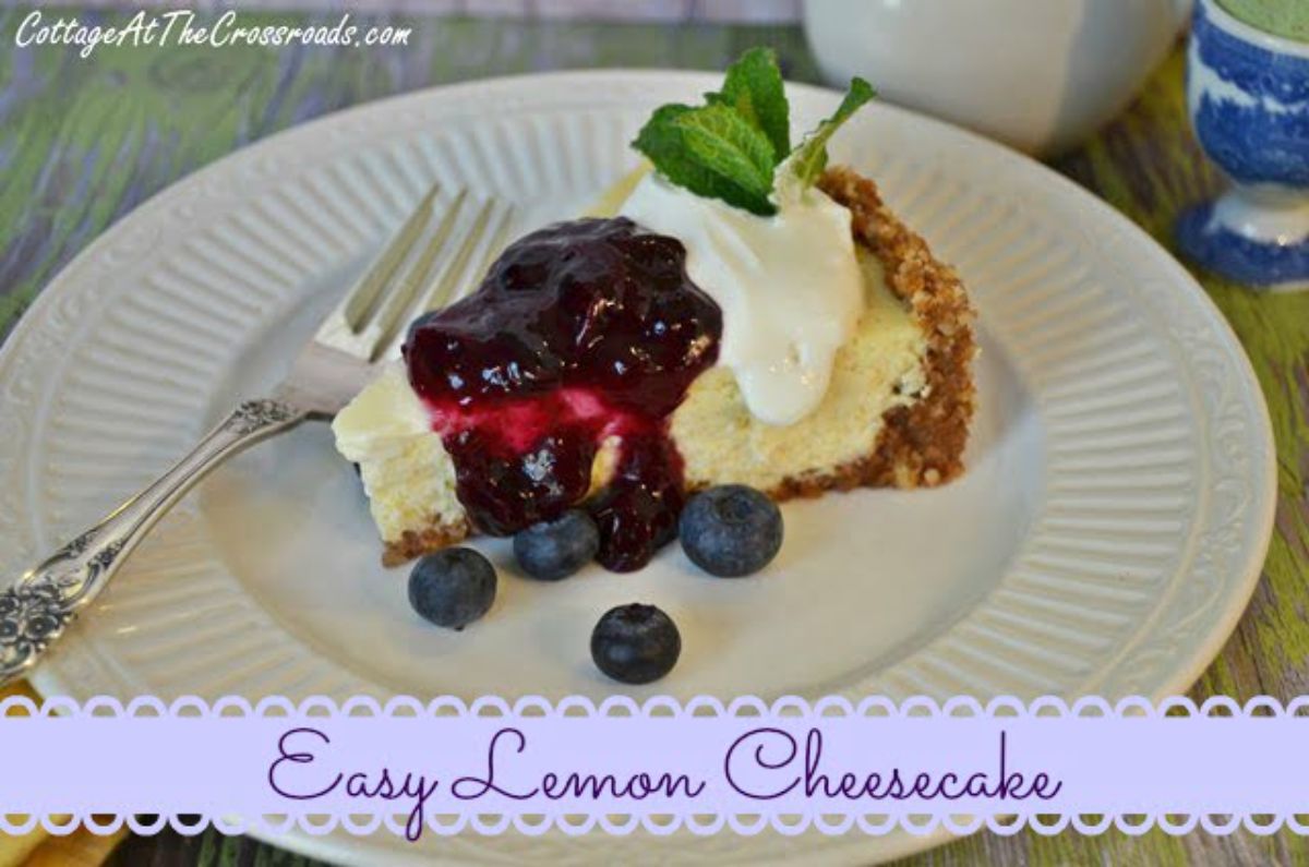 A piece of lemon cheesecake with blueberry topping on a white plate with a fork.