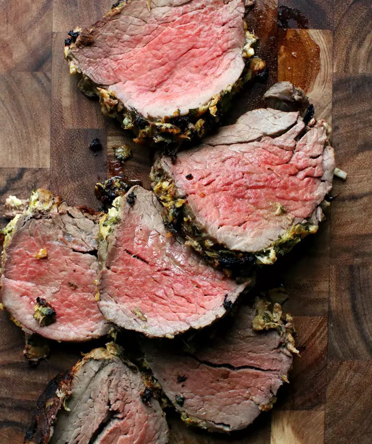 Sliced horseradish-crusted beef tenderloin on a wooden tray.