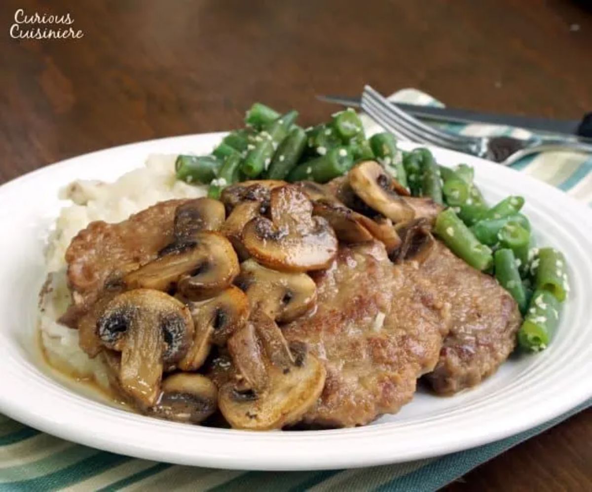 Scrumptious venison marsala with green on a white plate.