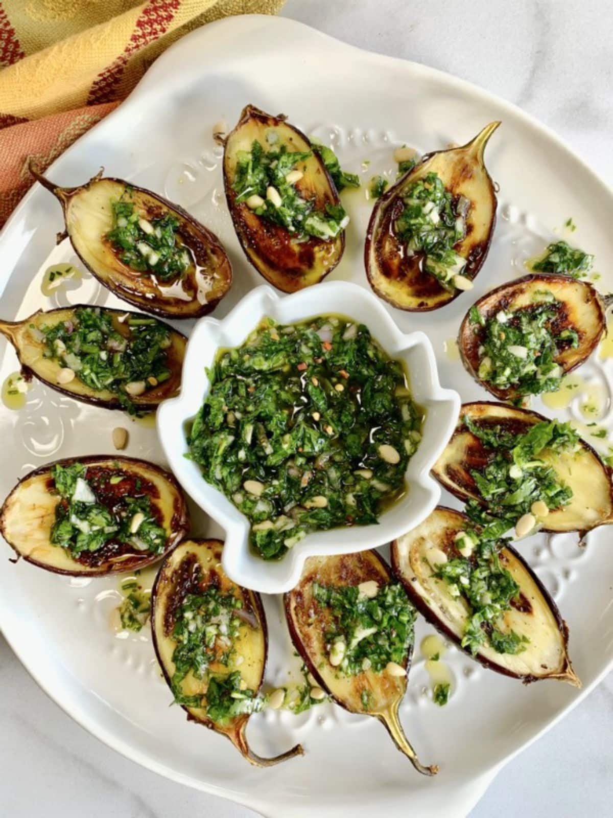 Tasteful baby eggplant with italian style salsa with a bowl of dip on a white tray.