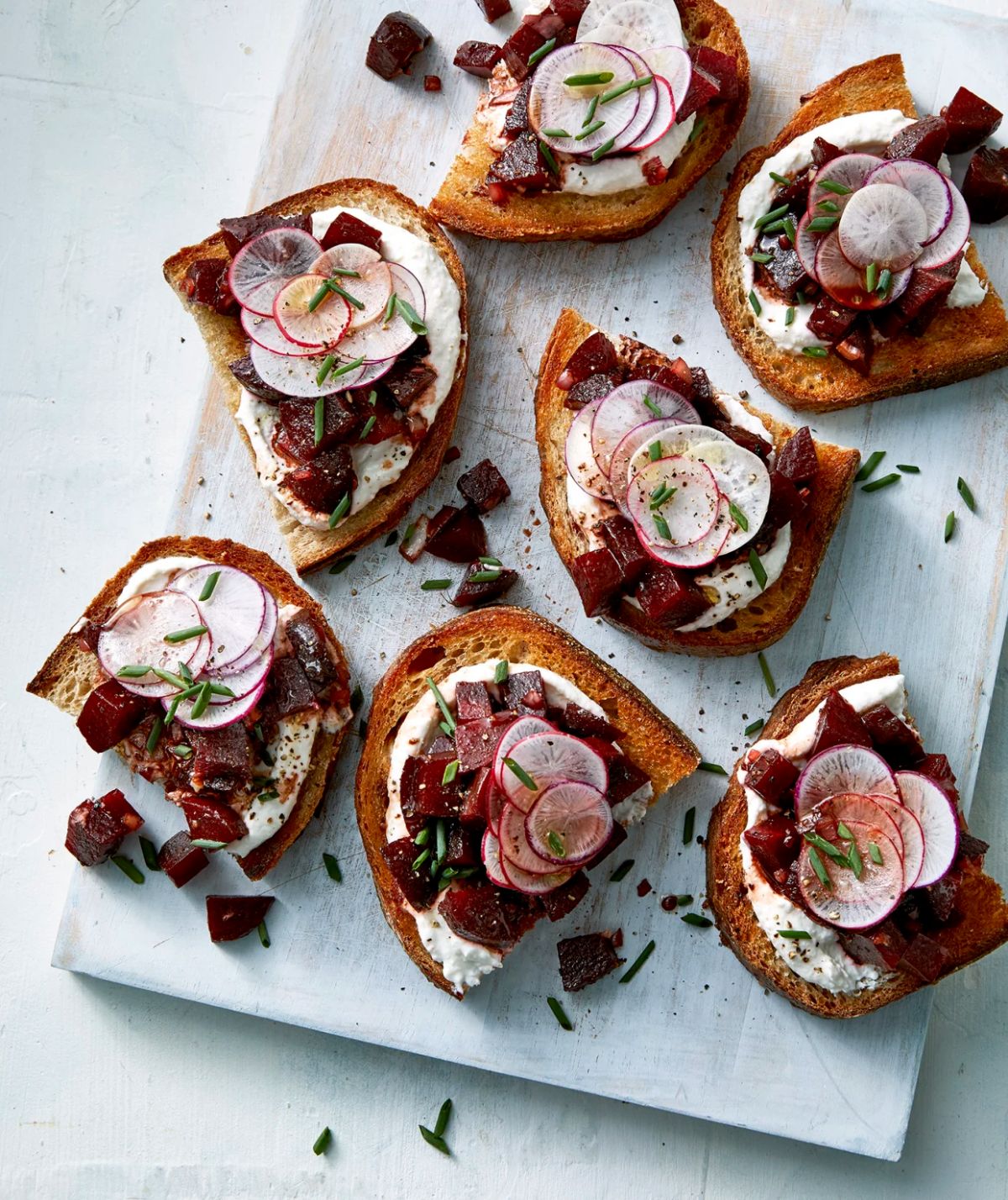 Scrumptious marinated beet toasts with yogurt on a wooden tray.