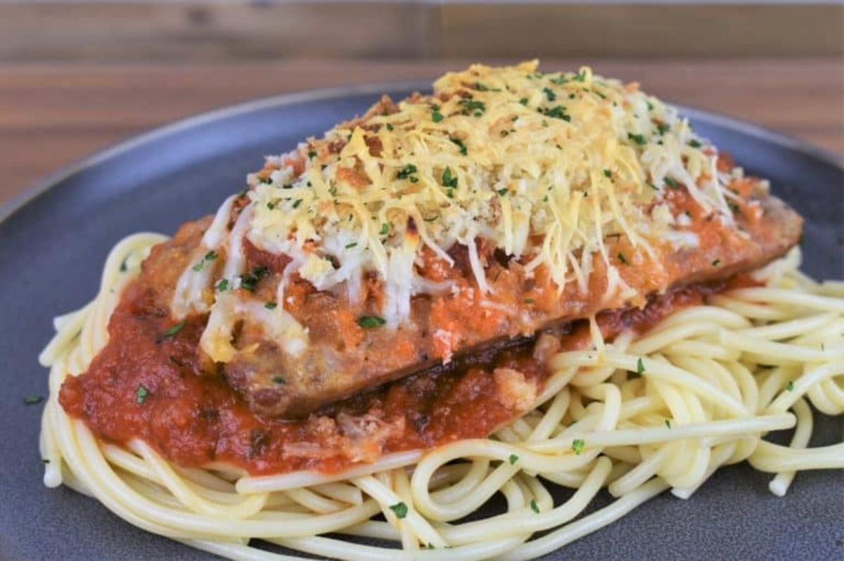 Scrumptious italian sausage parmigiana on a gray plate.