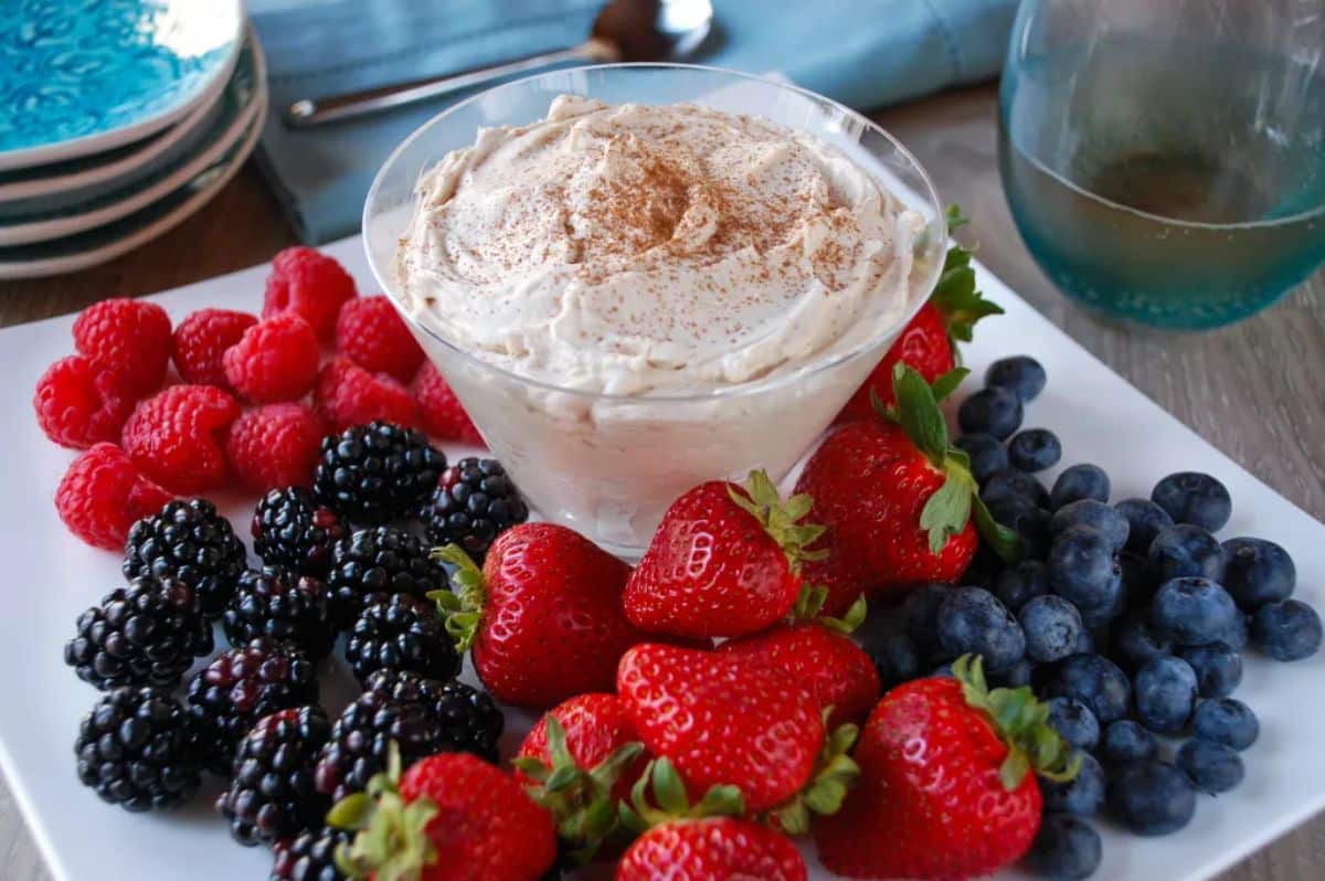 Creamy kahlua dessert dip in a glass bowl with fruits on a tray.
