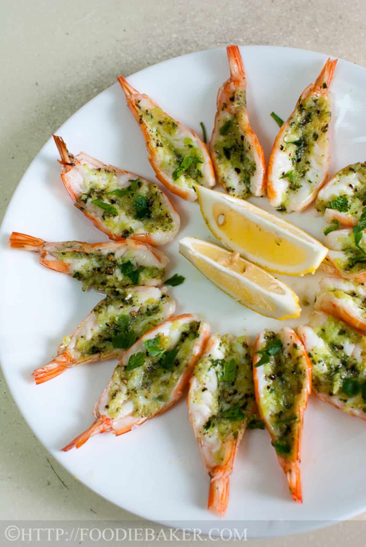 Flavorful roasted butterflied prawns with lemon wedges on a white plate.