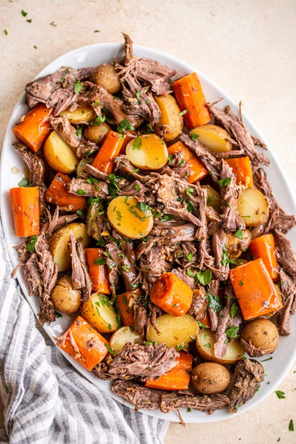 Mouth-watering slow cooker venison roast on a white tray.