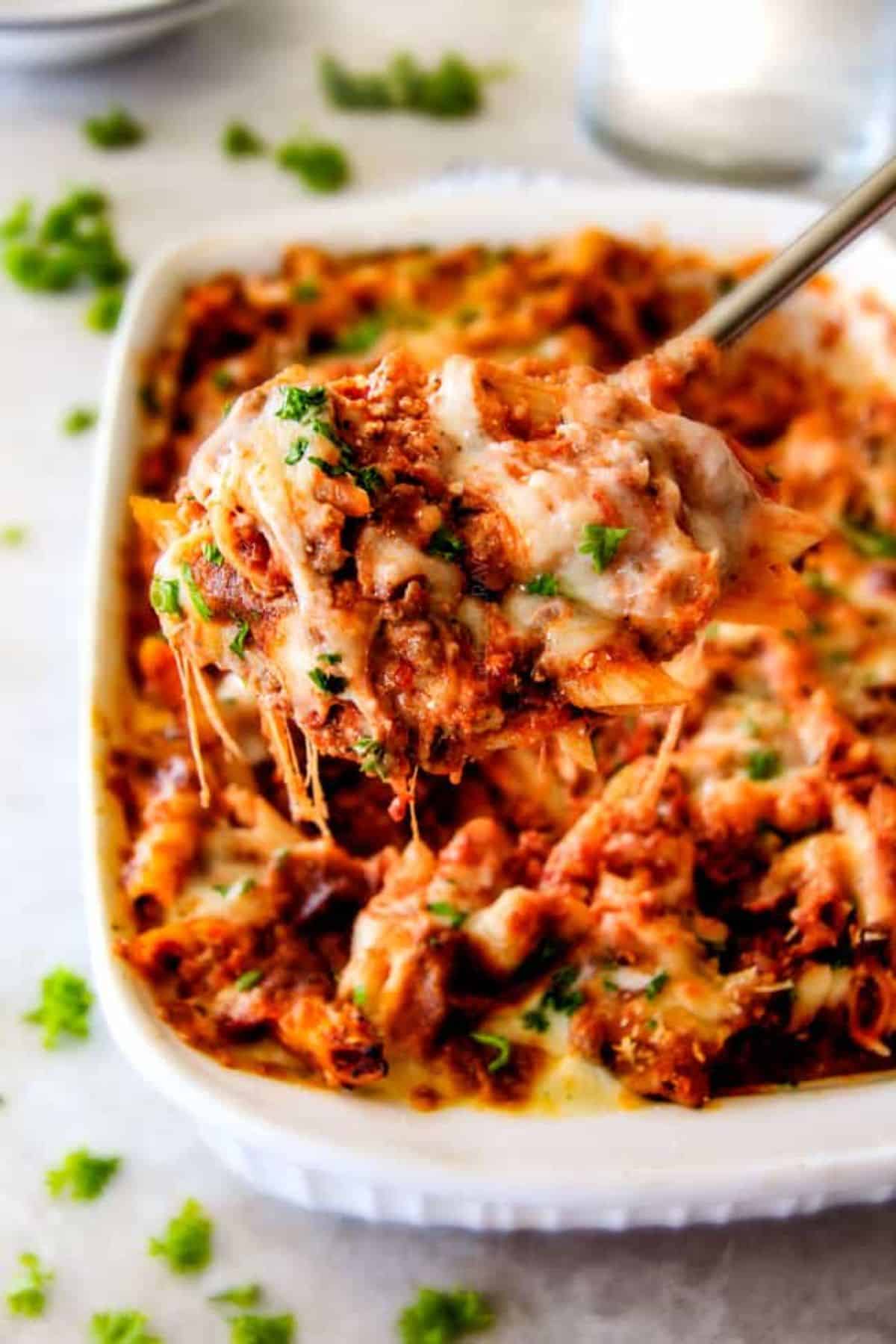 Juicy baked penne in a white casserole and on a spatula.