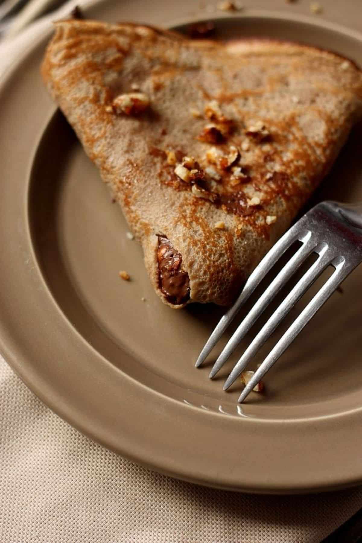 Scrumptious pancake with chestnuts on a plate with a fork.