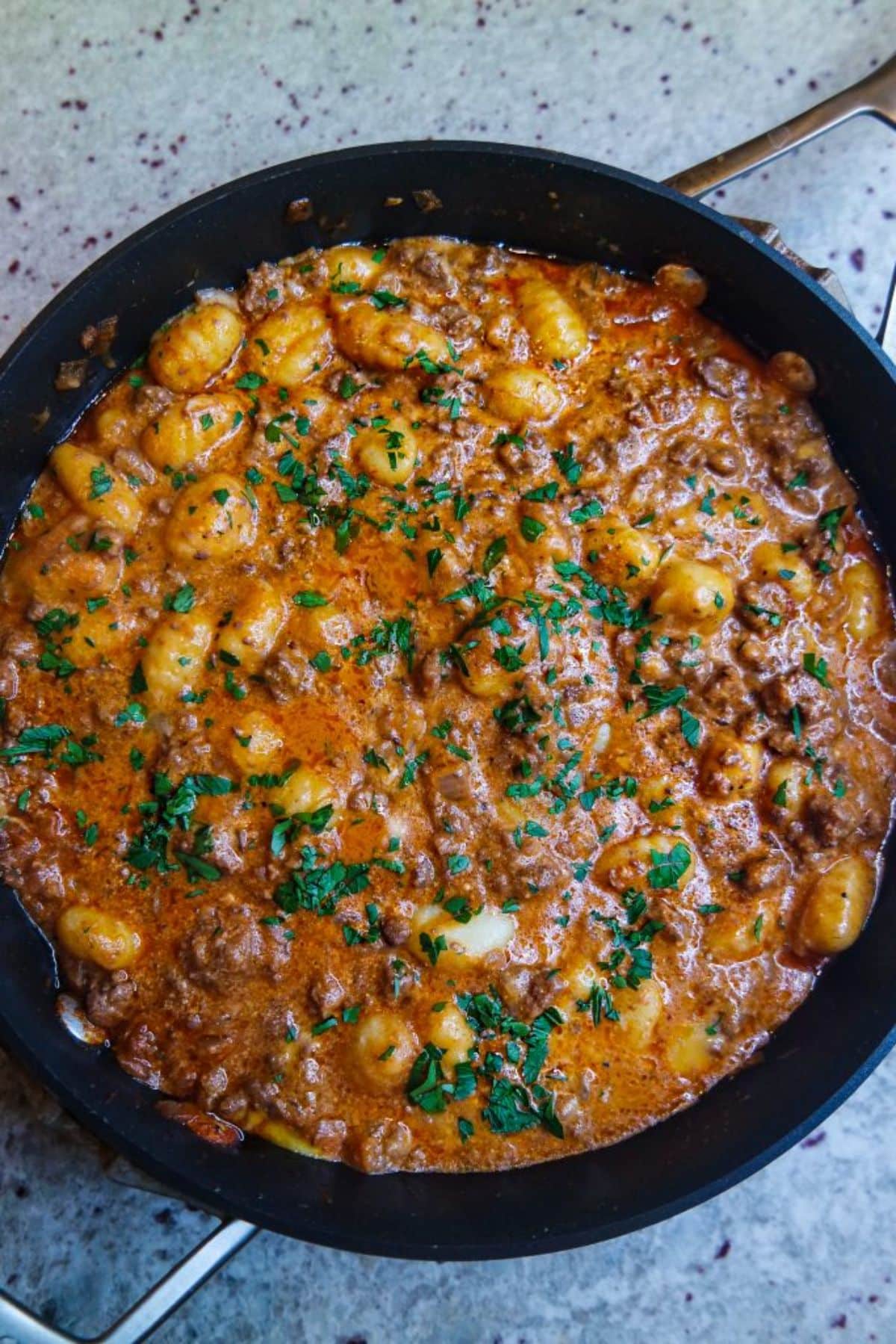 Juicy cheesy bison gnocchi in a black skillet.