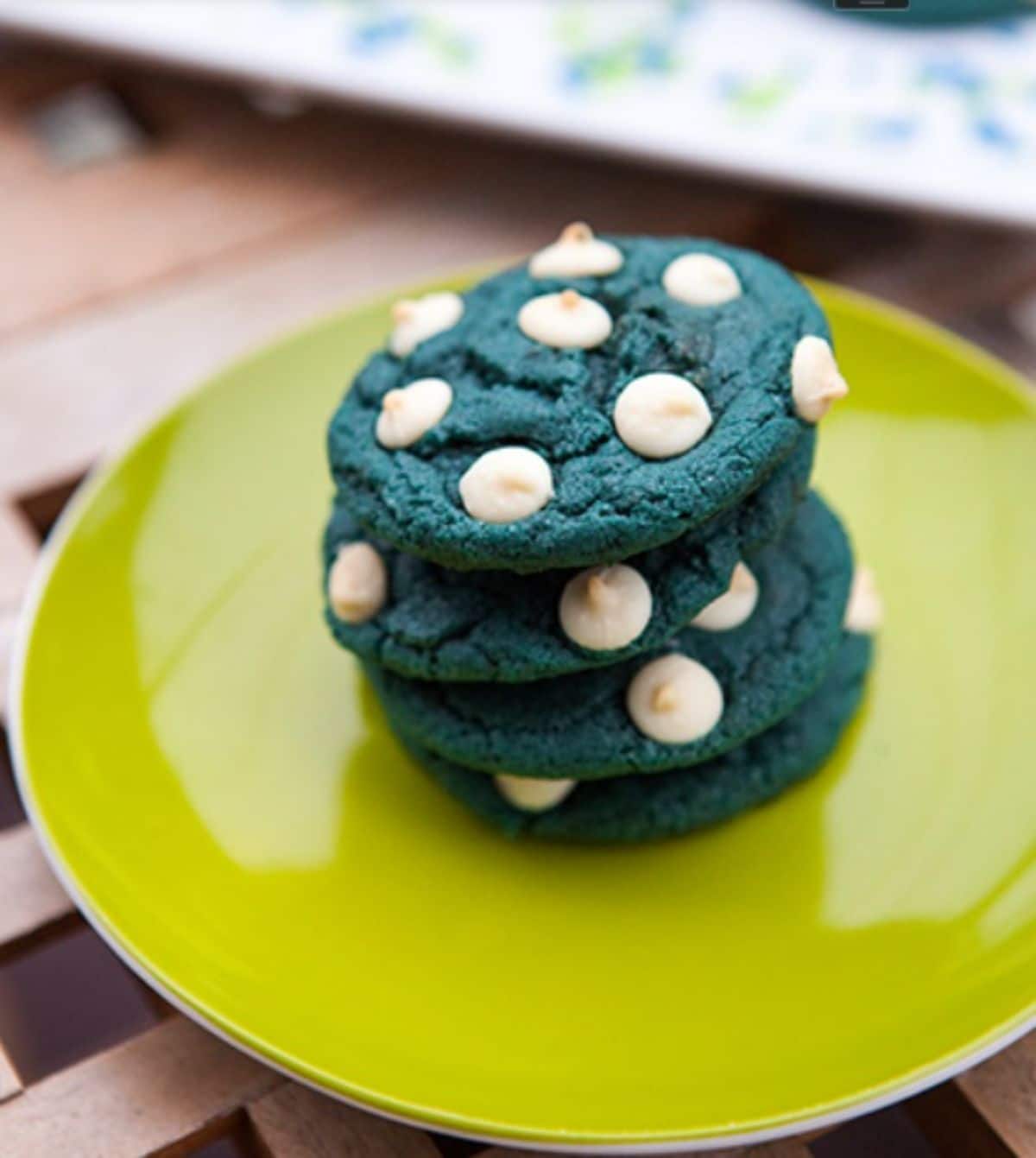 A pile of blue velvet white chocolate chip cookies on a green plate.