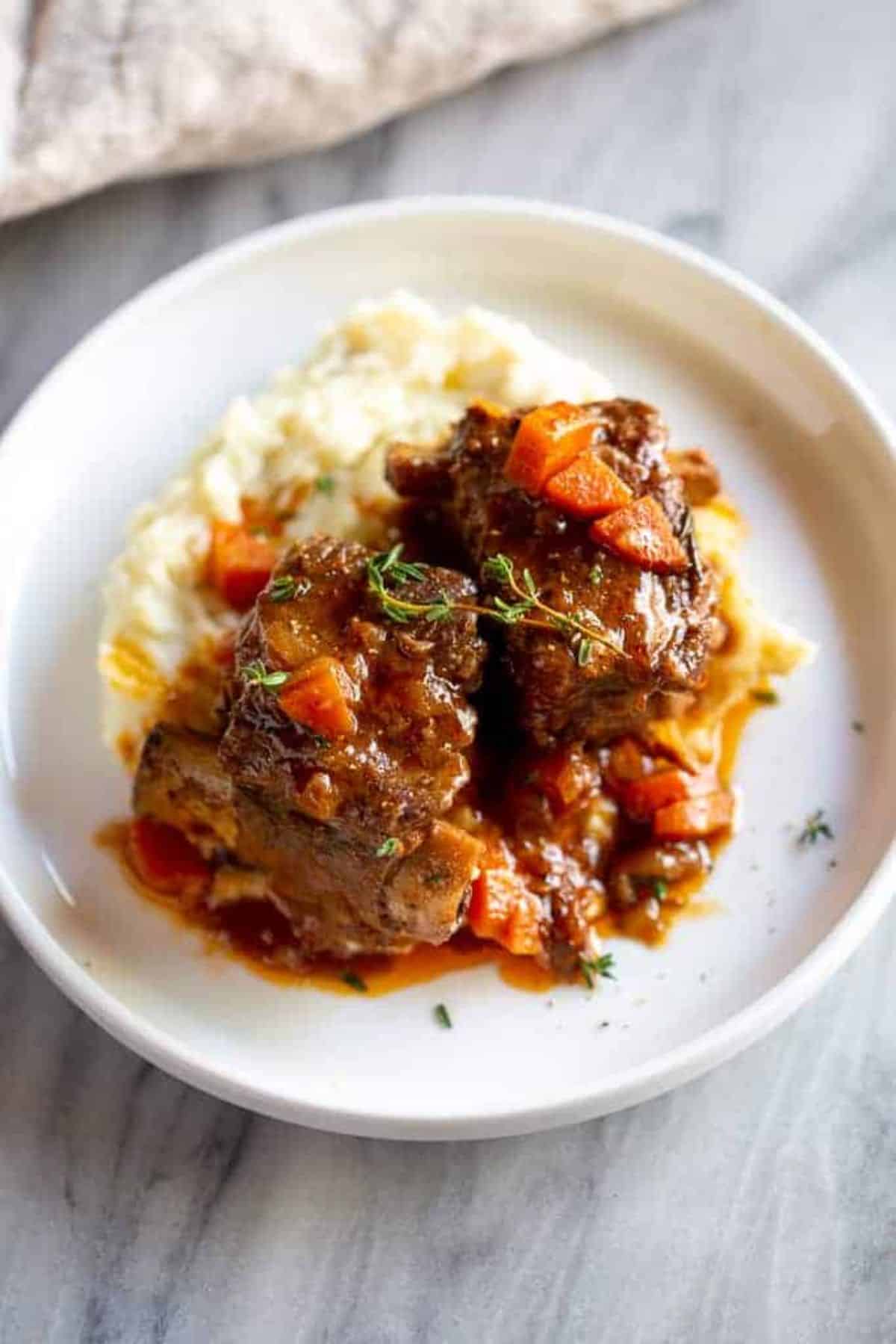 Mouth-watering braised short ribs on a white plate.