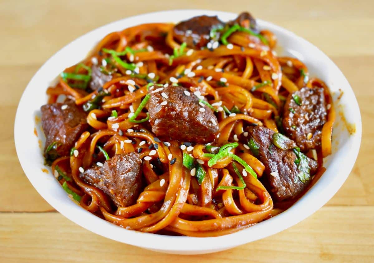 Flavorful elk steak gochujang noodles in a white bowl.