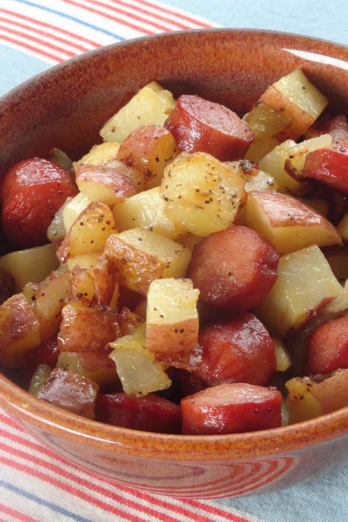 Tasty hot dog and potato hash in a bowl.