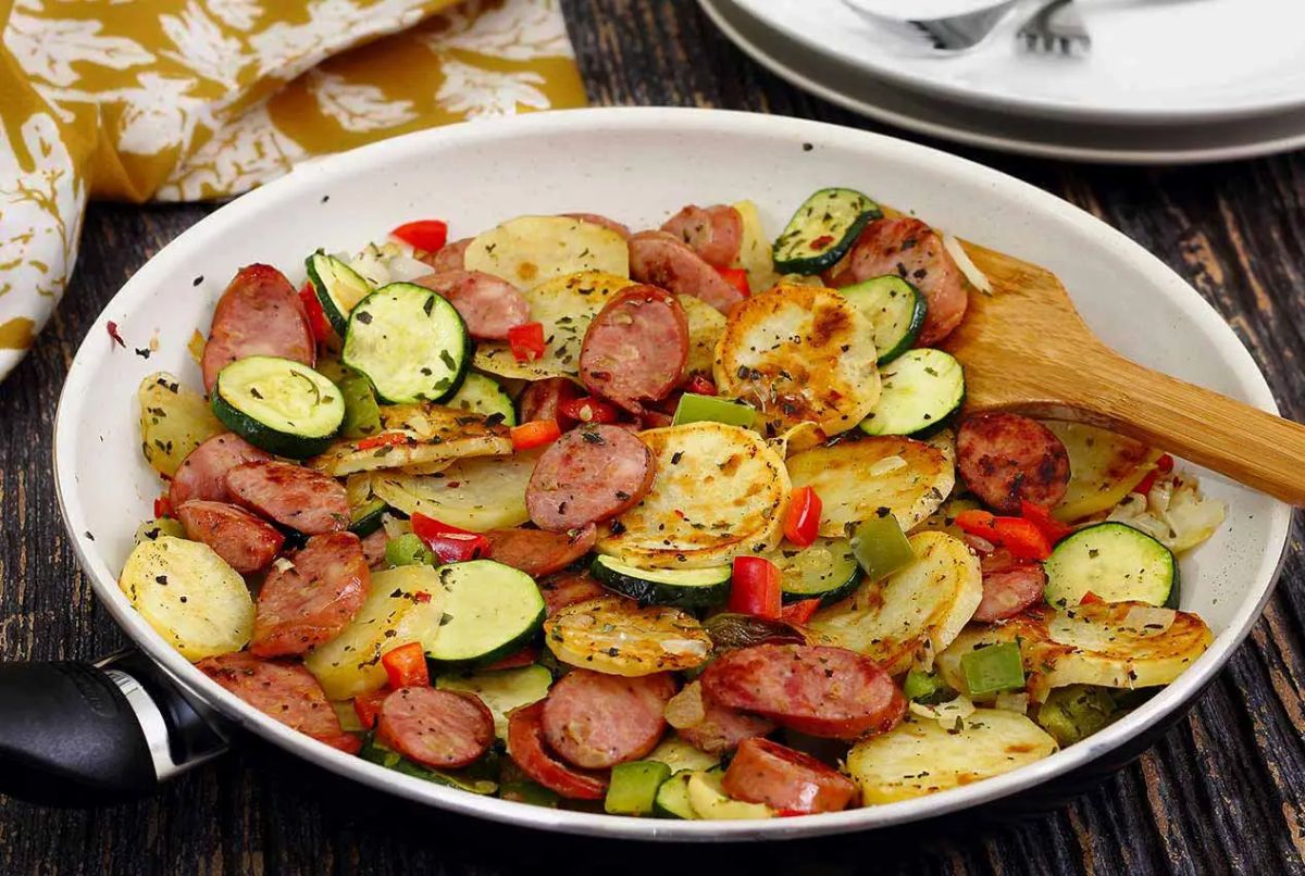 Flavorful italian sausage & potato skillet with a wooden spatula.