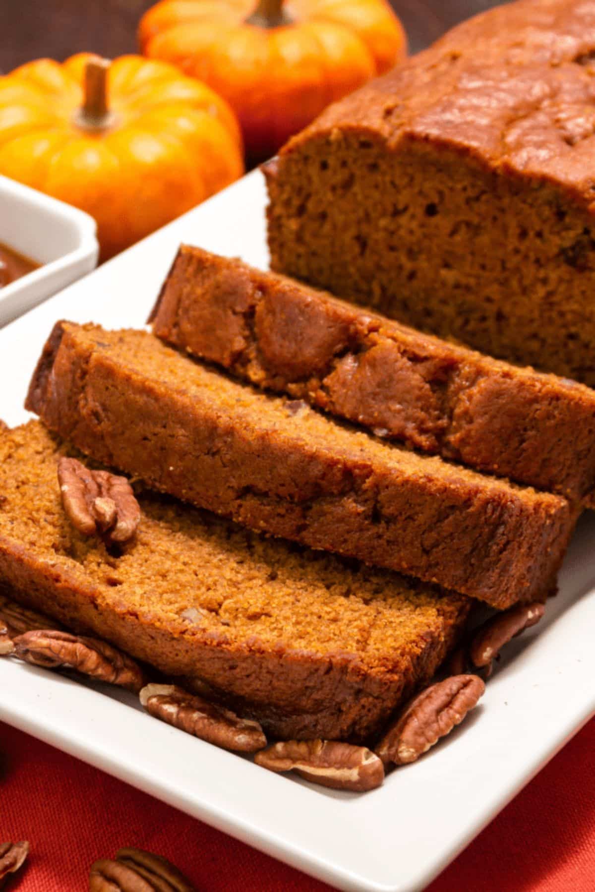Partially sliced pumpkin bread on a white tray.
