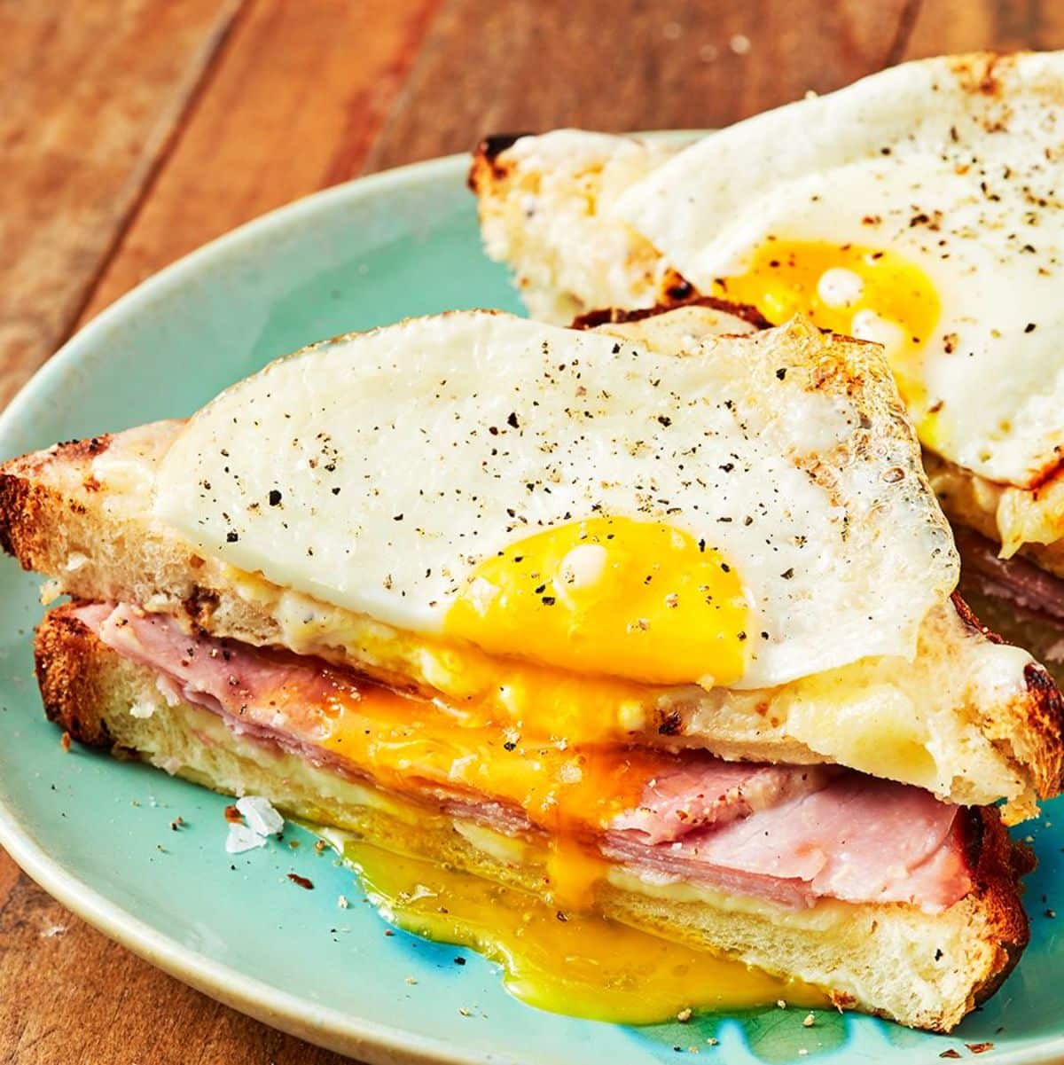 Juicy croque madame sandwiches on a blue plate.