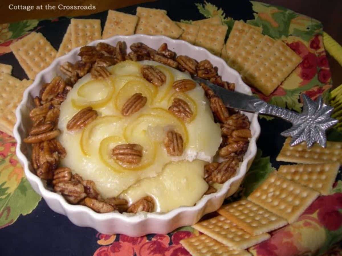 Scrumptious baked brie with candied lemon peelin a white bowl.