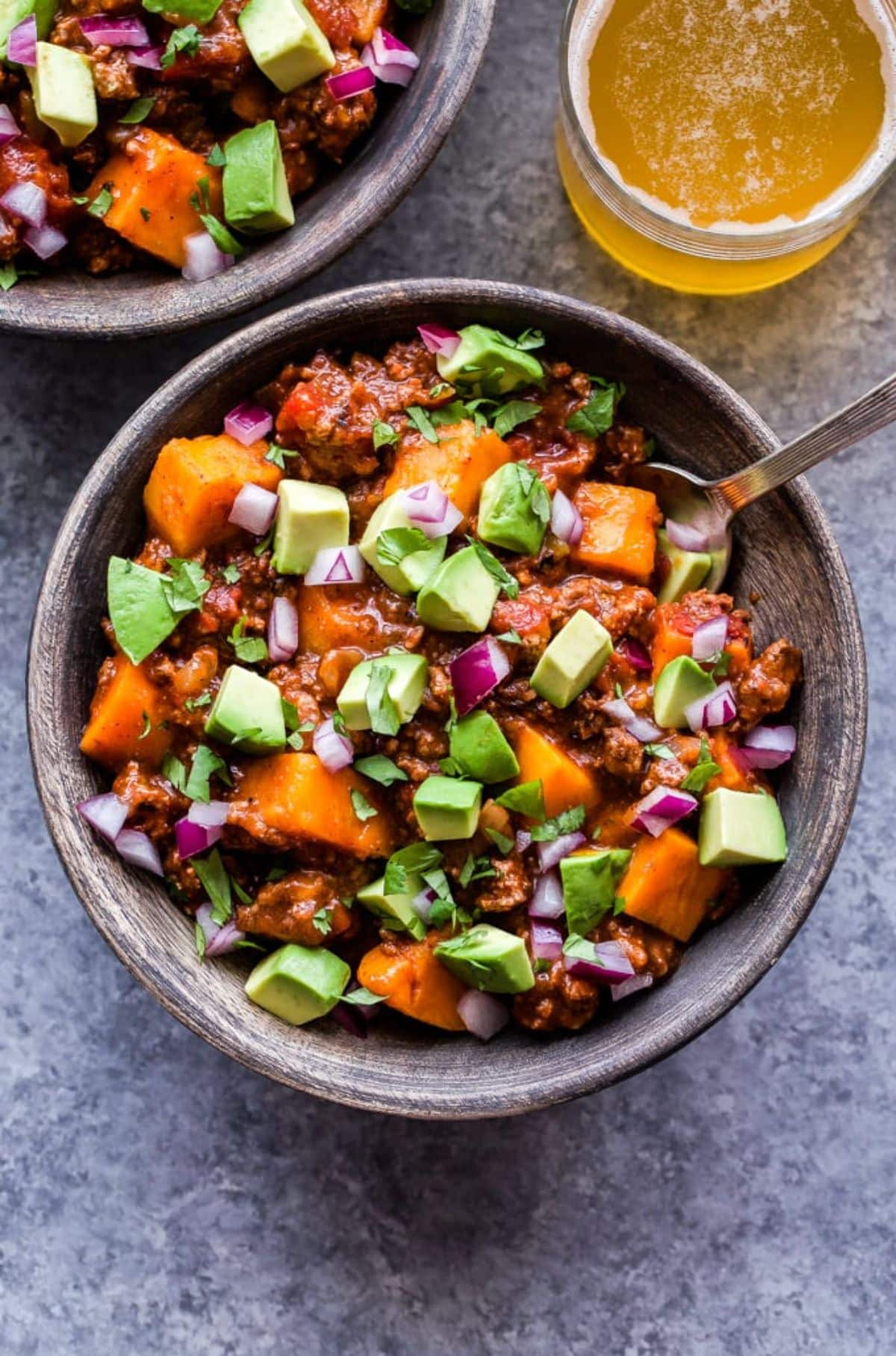 Mouth-watering slow cooker bison sweet potato chiliin a bowl with a spoon.