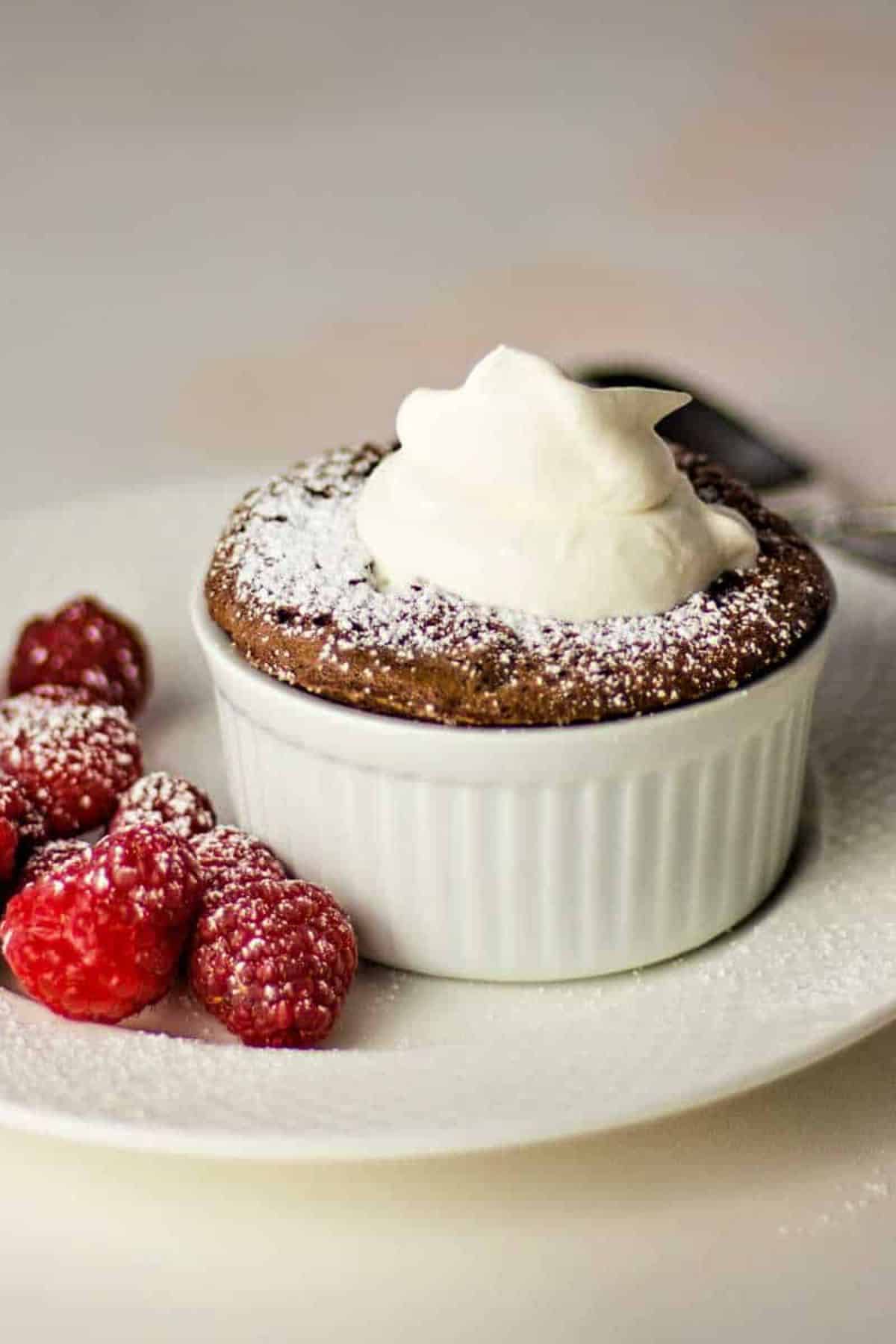 Scrumptious chocolate souffle cake in a small bowl on a plate.