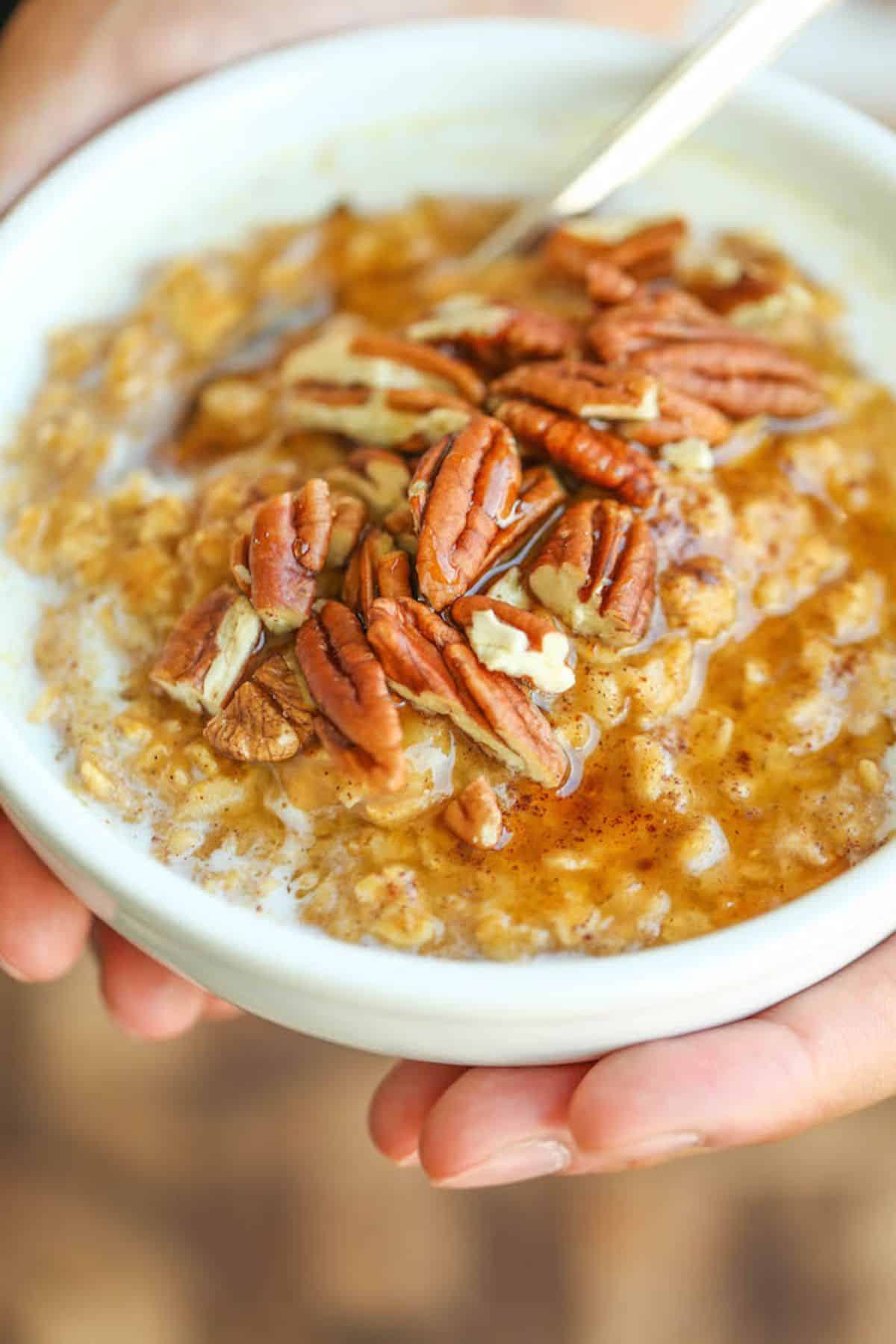 Healthy pumpkin pie oatmeal in a white bowl with a spoon.