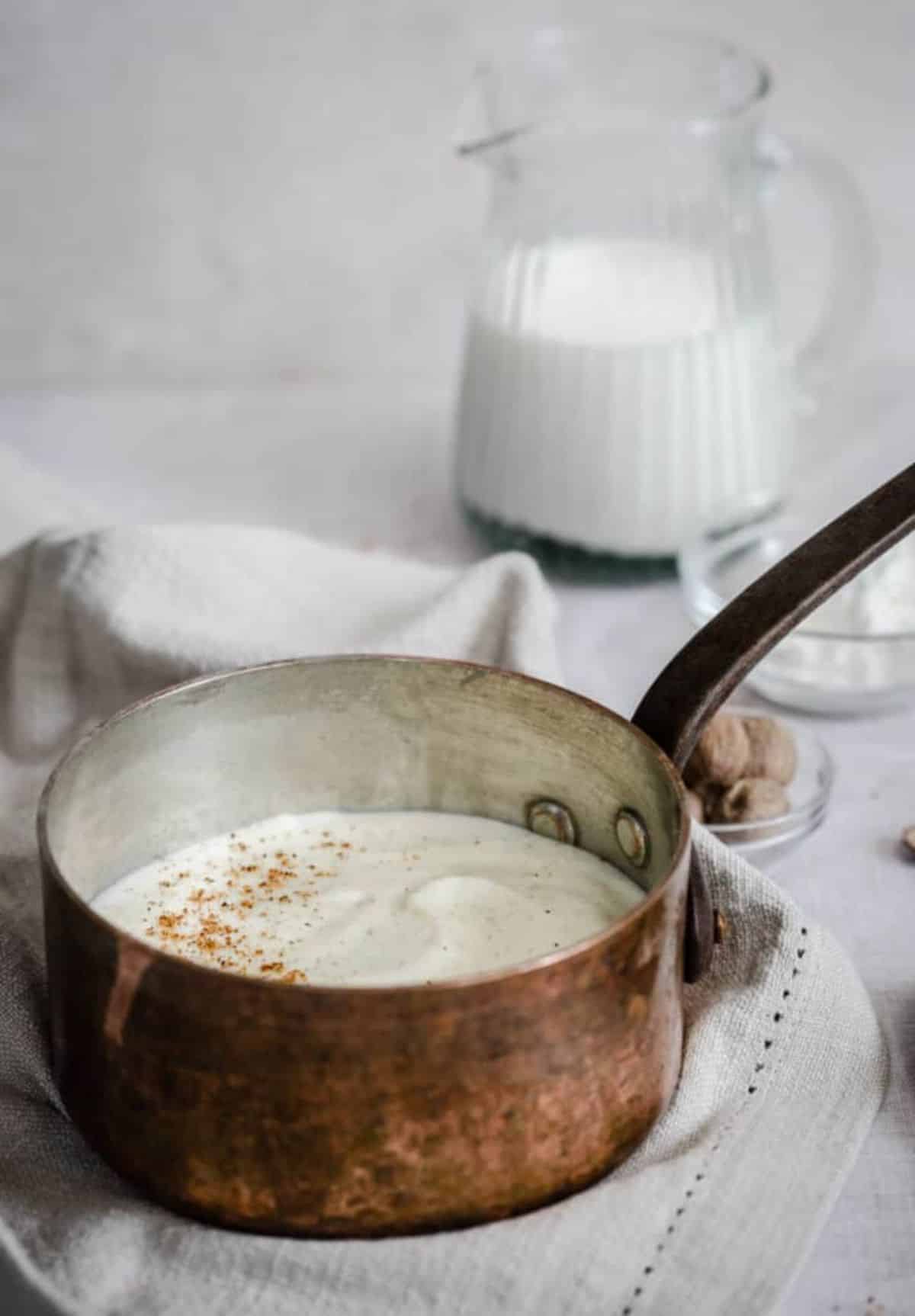 Creamy béchamel sauce in a small pot.