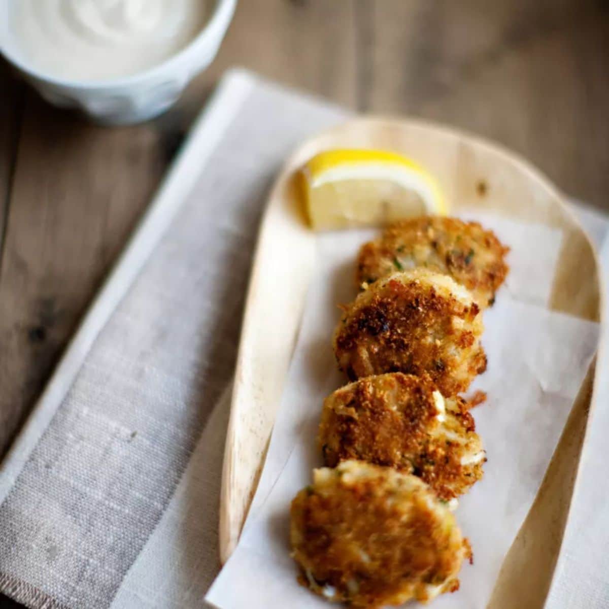 Crunchy crab cakes with horseradishon a wooden tray.