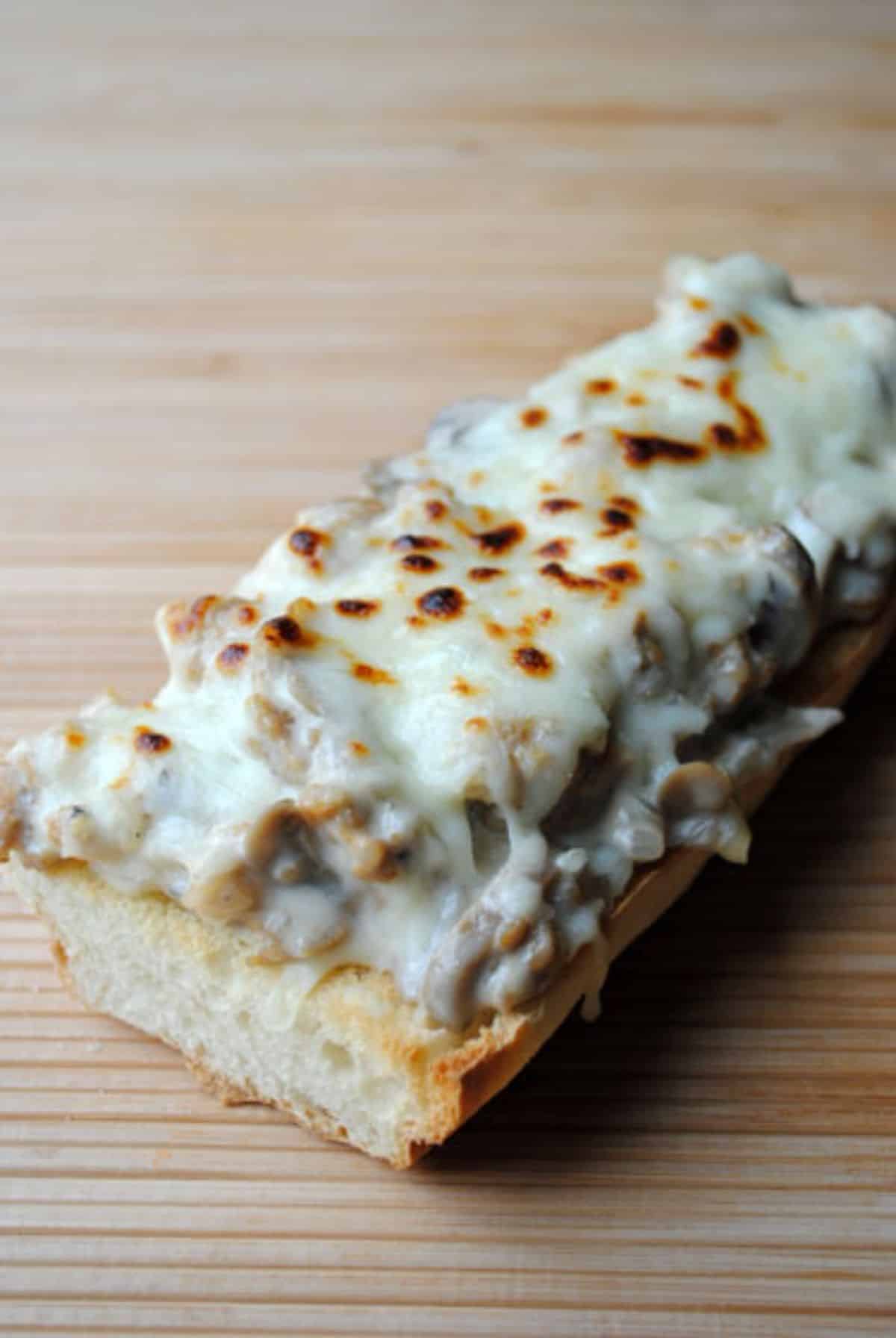 A piece of sausage alfredo french bread pizza on a table.