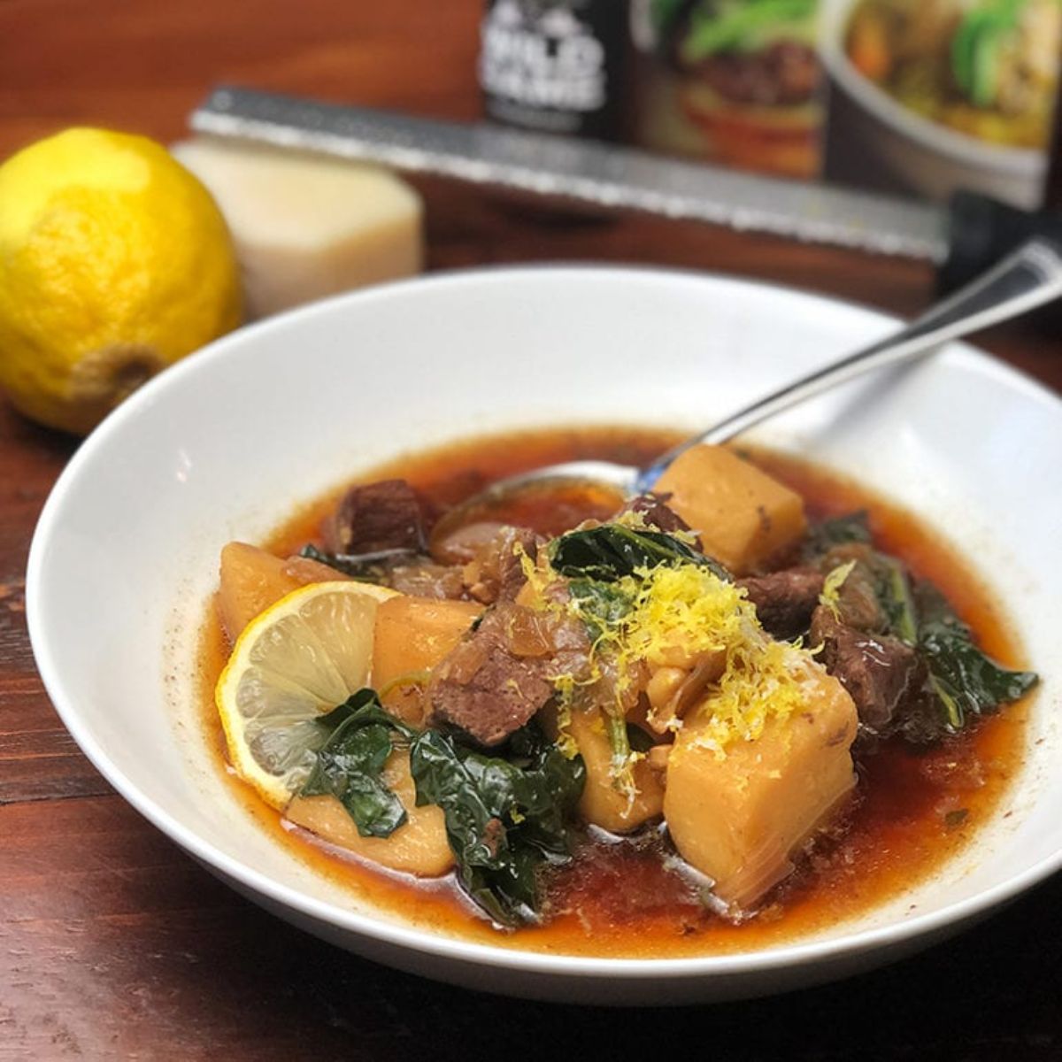 Healthy venison tuscan-inspired soup in a white bowl with a spoon.