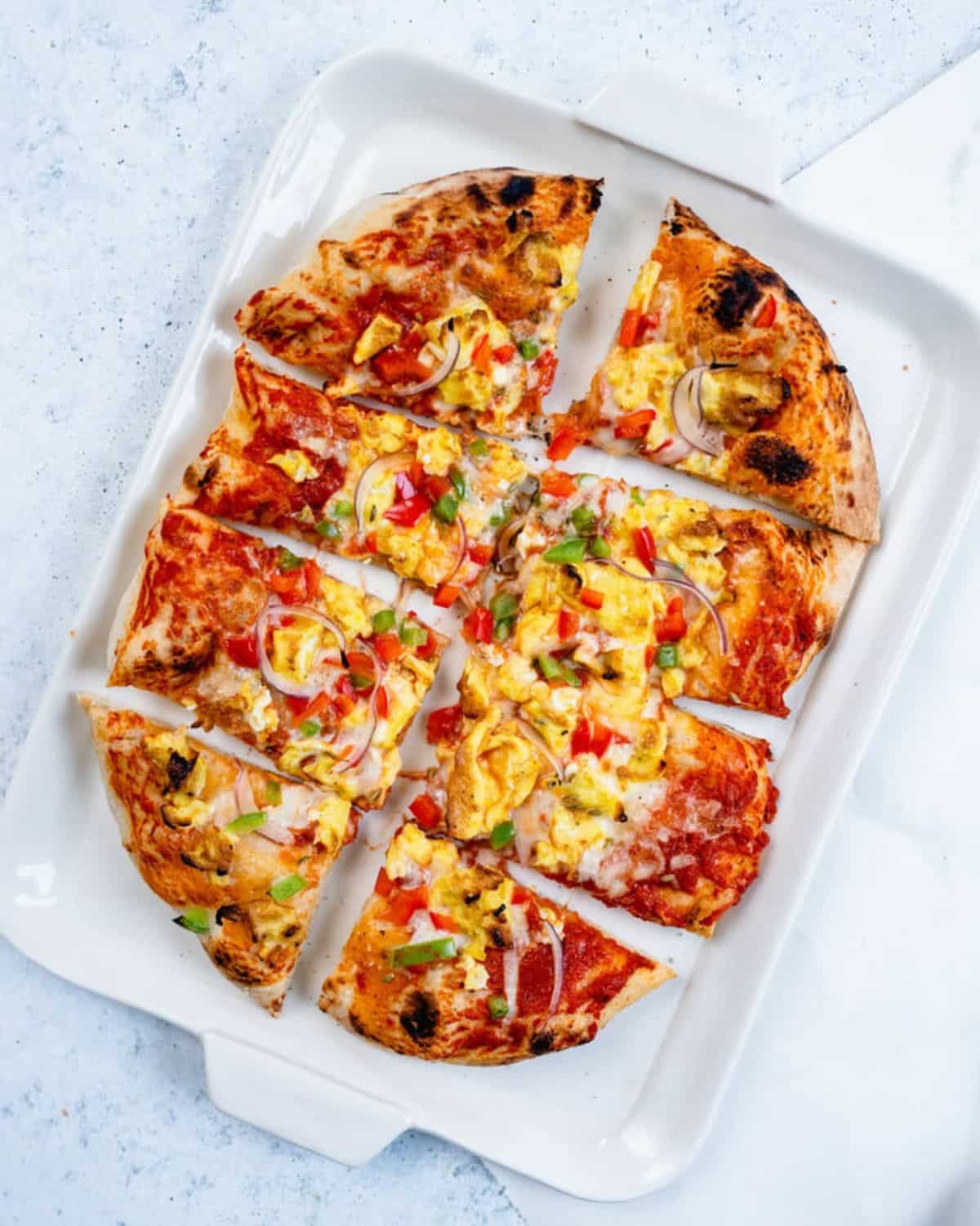 Sliced breakfast pizza on a white tray.