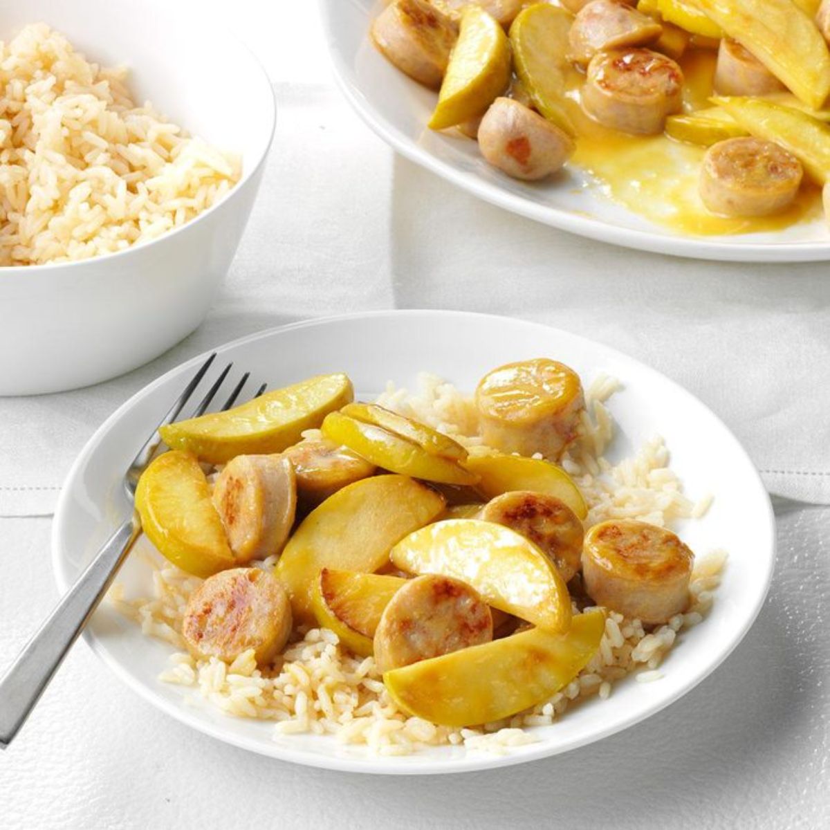 Tasteful honey mustard apple chicken sausage with rice on a white plate with a fork.