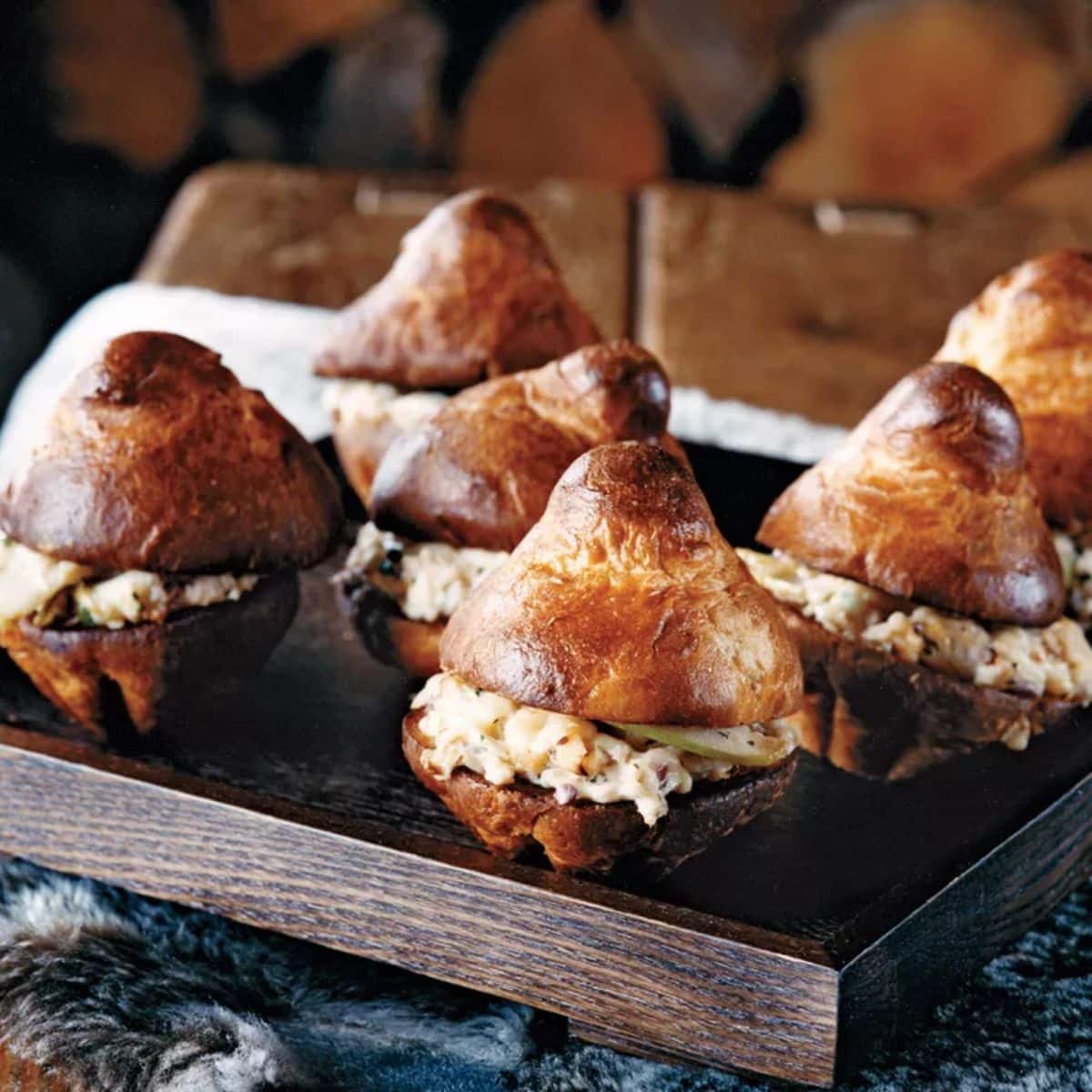 Mouth-watering brioche crab melts on a wooden tray.