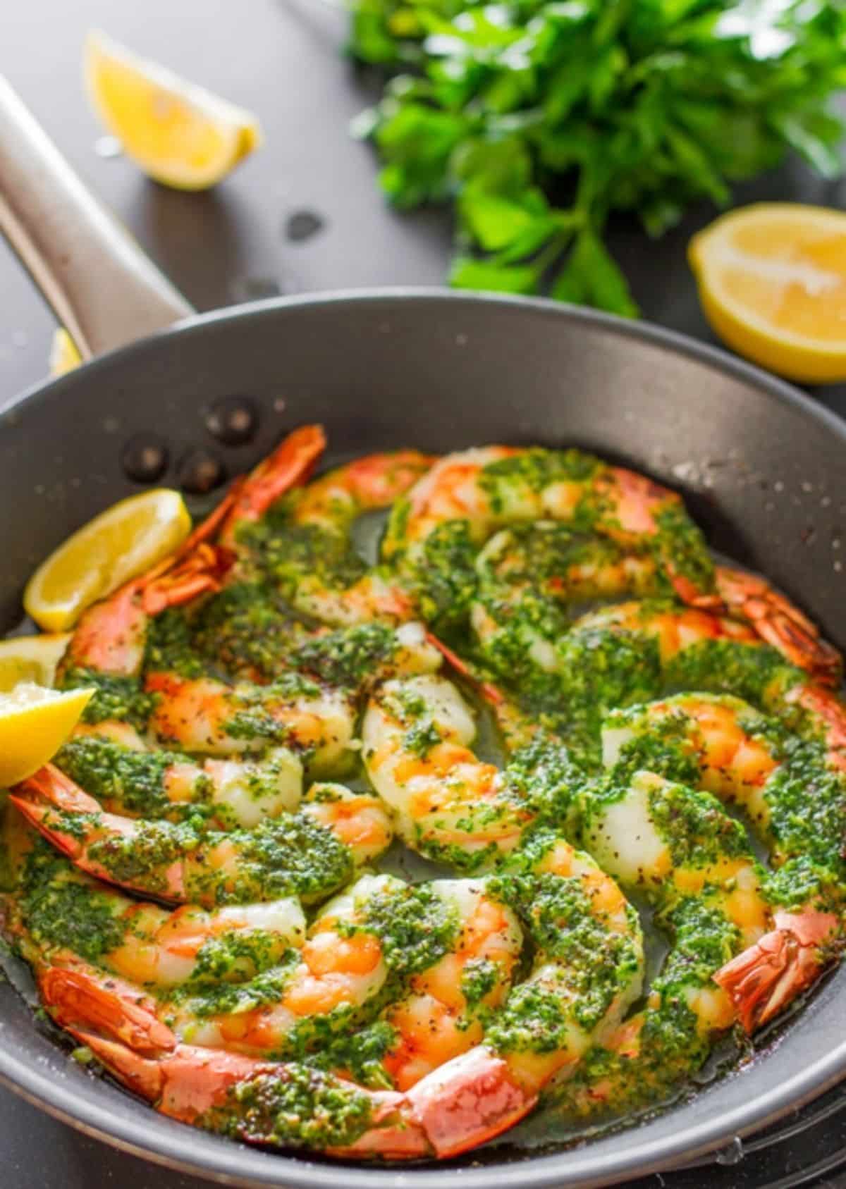 Juicy garlic and parsley shrimp in a black skillet.