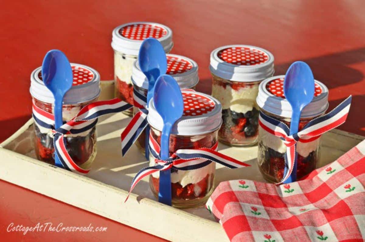 Flavorful patriotic dessert in jars on a wooden tray.