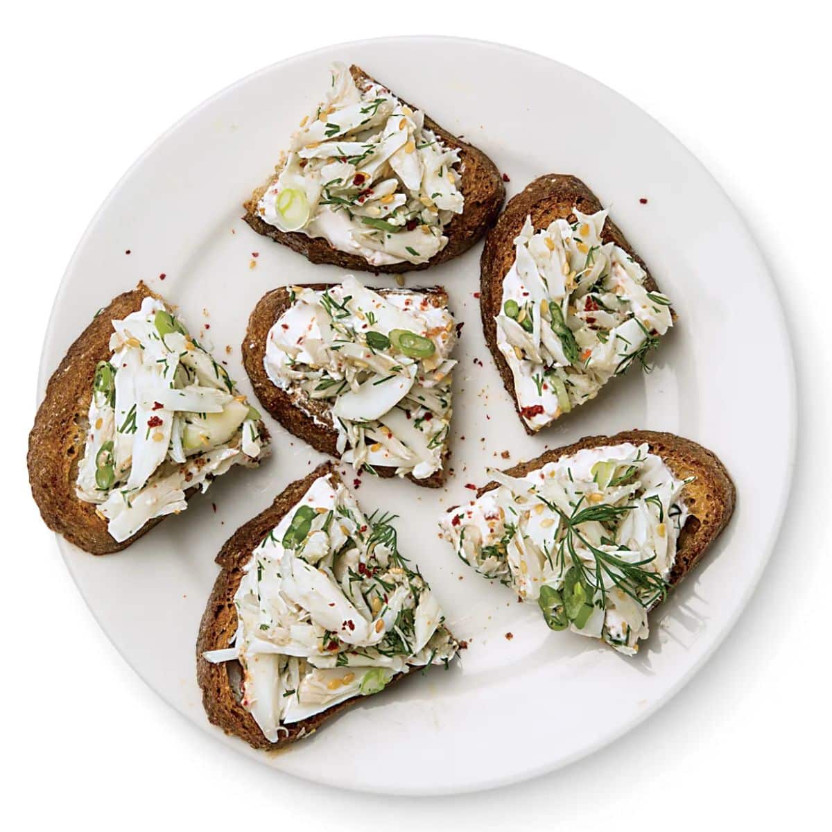 Flavorful crab toasts with yogurt on a white plate.