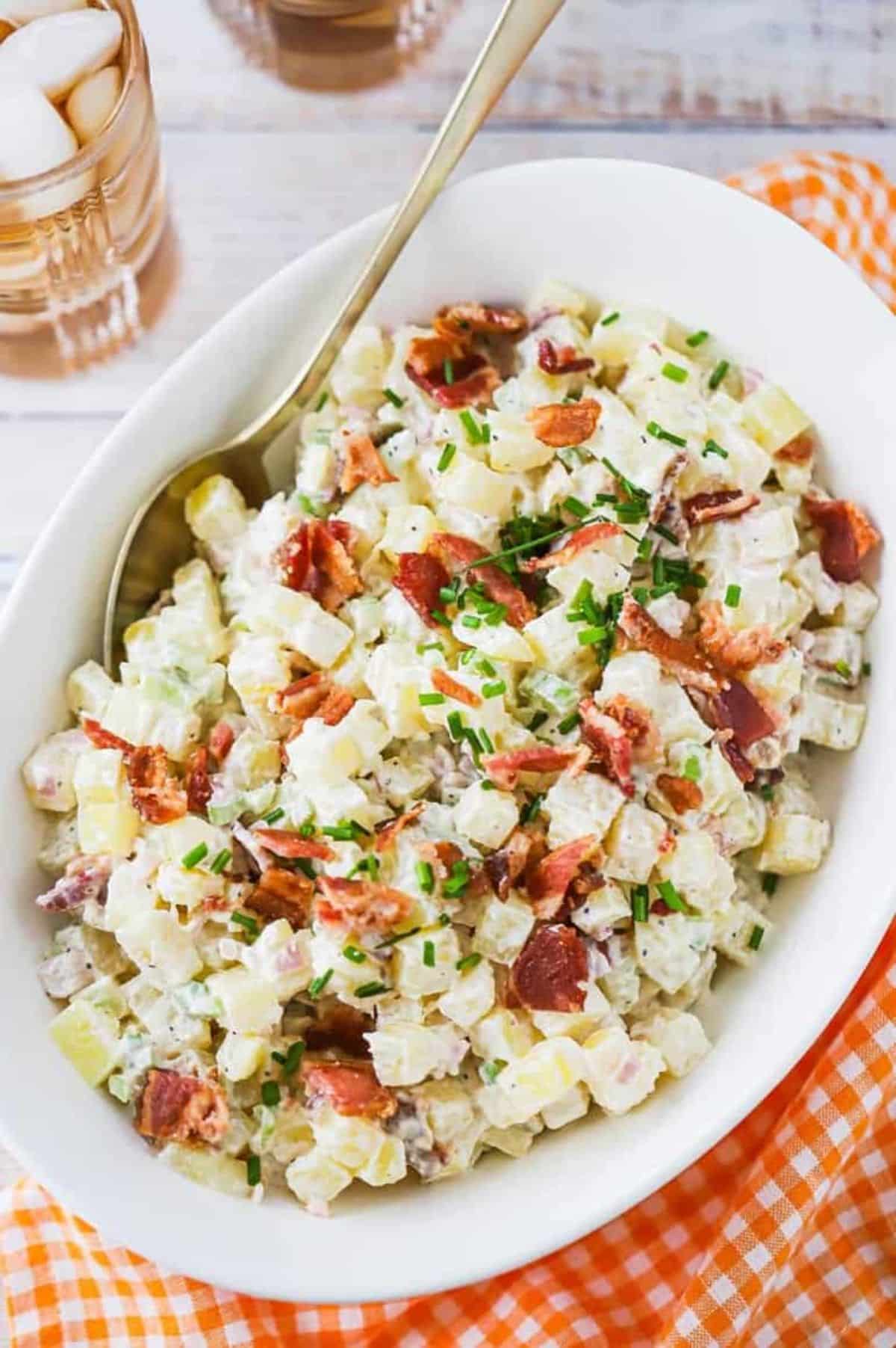 Tasty horseradish potato salad in a white bowl with a spoon.